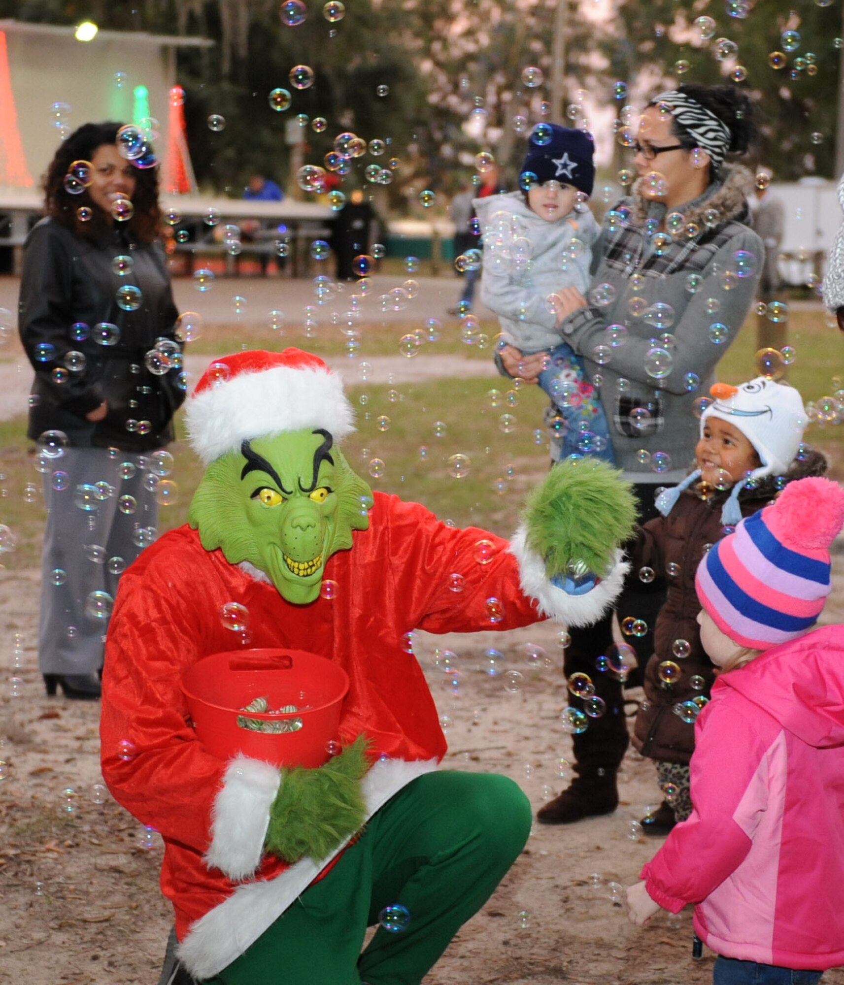 The Grinch plays in a swarm of bubbles with children of Keesler personnel during Keesler’s annual Christmas in the Park celebration at marina park Dec. 3, 2015, Keesler Air Force Base, Miss. The event, hosted by Outdoor Recreation, included a tree lighting ceremony, tour train rides, holiday music, cookie and ornament decorating, and visits with Santa. (U.S. Air Force photo by Kemberly Groue)