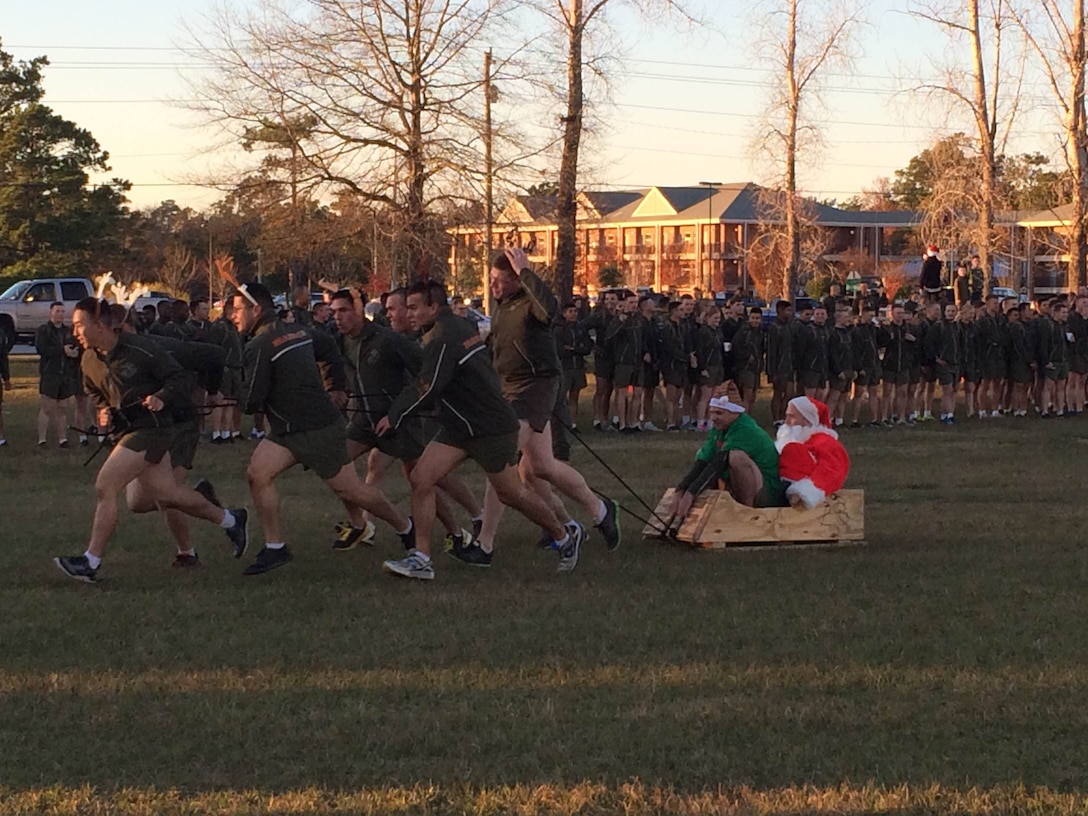 Utilities Instruction Company Marines, wearing antlers; pull Major Kirk A. Whittenberg, in a Santa suit; and First Sergeant Douglas M. Hester, in an elf costume; across the parade field in a sleigh as part of the Marine Corps Engineer School Commanding Officer's Holiday Sleigh Relay Race at Courthouse Bay, Camp Lejeune, N.C. on Dec. 4, 2015. 

