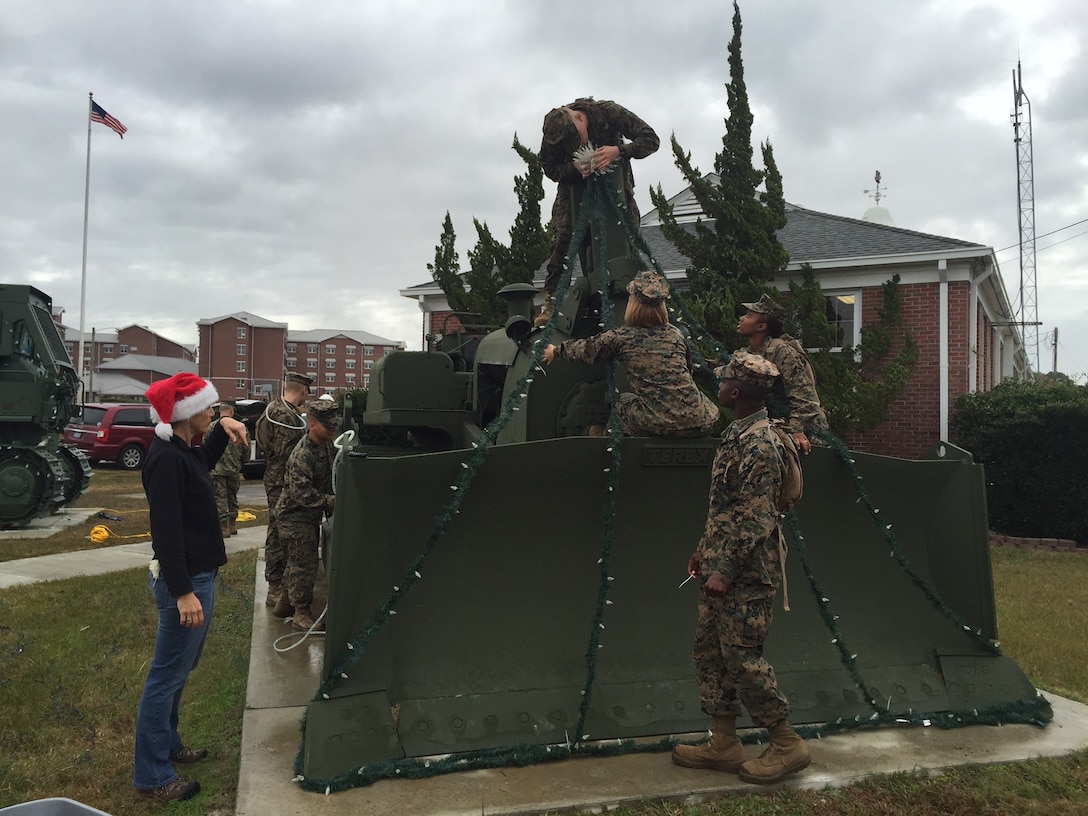 Marines and Family Readiness volunteers string up lights on one of the bulldozers in front of the Marine Corps Engineer School headquarters building in order to decorate for the holidays at Courthouse Bay, Camp Lejeune, N.C.

