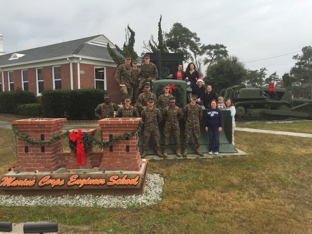Marines and Family Readiness volunteers string up lights on the bulldozers and trees, and hang garland and bows in front of the Marine Corps Engineer School headquarters building in order to decorate for the holidays at Courthouse Bay, Camp Lejeune, N.C.