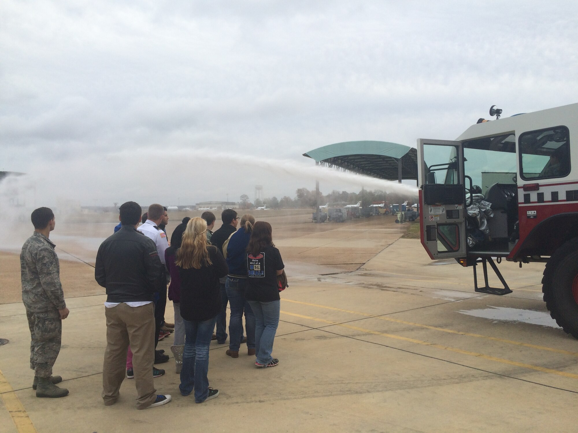Twelve students from Calhoun County Career and Technical Center in Calhoun City, Mississippi, watch as Senior Airman Kameron Scott, 14th Civil Engineer Squadron firefighter, fires the water cannon on one of the McAllister Fire Station fire trucks Dec. 2 at Columbus Air Force Base, Mississippi. The students visited the base to learn more about military first response units. (U.S. Air Force photo/2nd Lt. Lauren Woods)