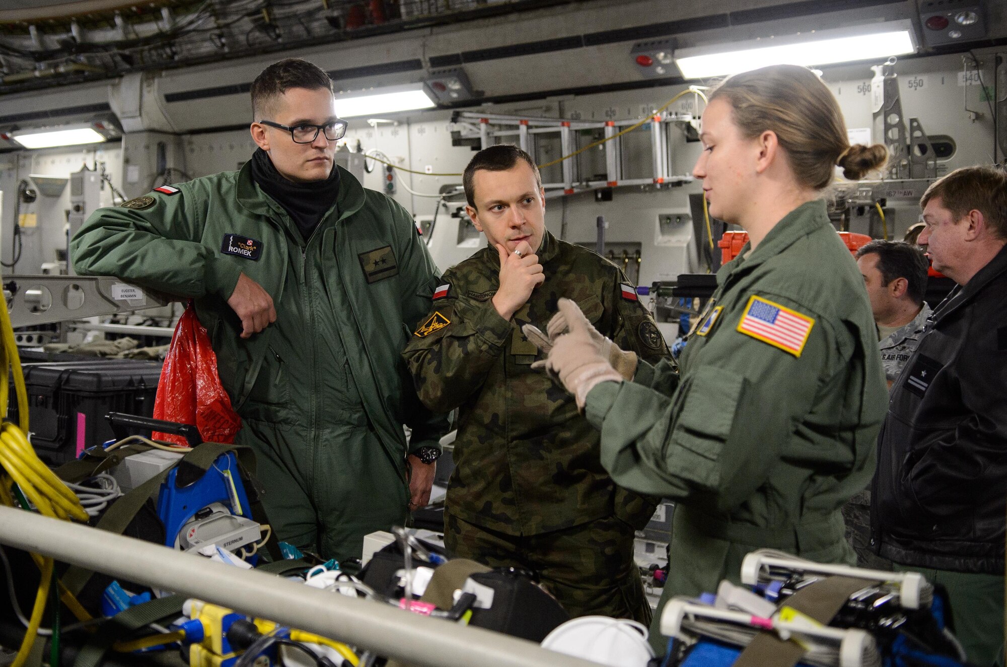 Polish Air Force 2nd Lts. Krzysztof Romek, left, and Andrzej Nartonowicz, center, both aeromedical evacuation doctors, listen to U.S. Air Force Staff Sgt. Jesse Visser, a 10th Expeditionary Aeromedical Evacuation Flight duty controller, explain the mission of the 10th EAEF Dec. 2, 2015, at Ramstein Air Base, Germany. Romek and Nartonowicz are two members of the only Polish AE team and are familiarizing themselves with practices used by U.S. Airmen. (U.S. Air Force photo/Staff Sgt. Armando A. Schwier-Morales)