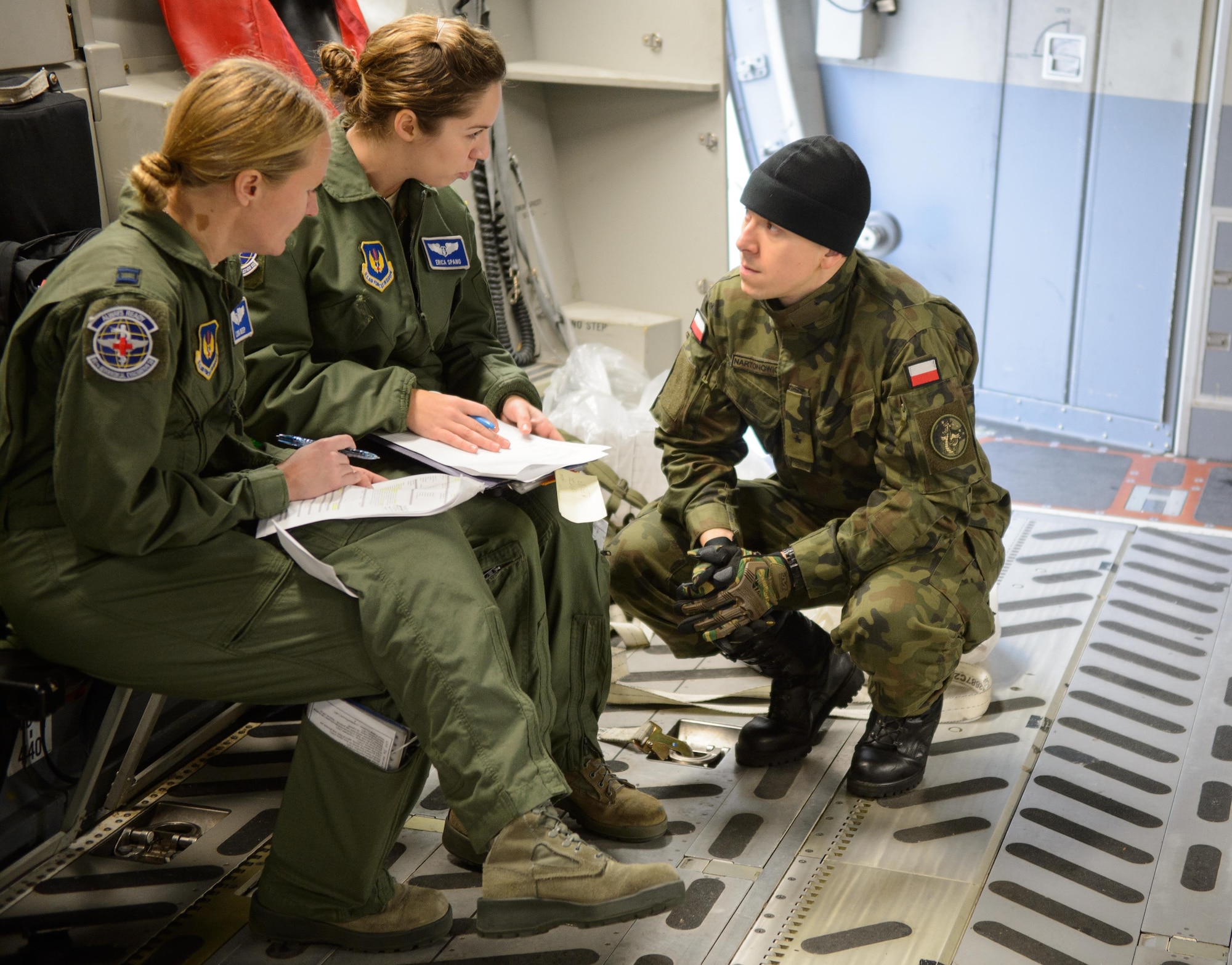 Polish Air Force 2nd Lt. Andrzej Nartonowicz, an aeromedical evacuation doctor, listens to two 86th Aeromedical Evacuation Squadron Airmen as they prepare for a mock mission Dec. 3, 2015, at Ramstein Air Base, Germany. The 86th AES and other aeromedical evacuation specialists on Ramstein showcased procedures and tactics used to save lives for the developing Polish AE mission. (U.S. Air Force photo/Staff Sgt. Armando A. Schwier-Morales)