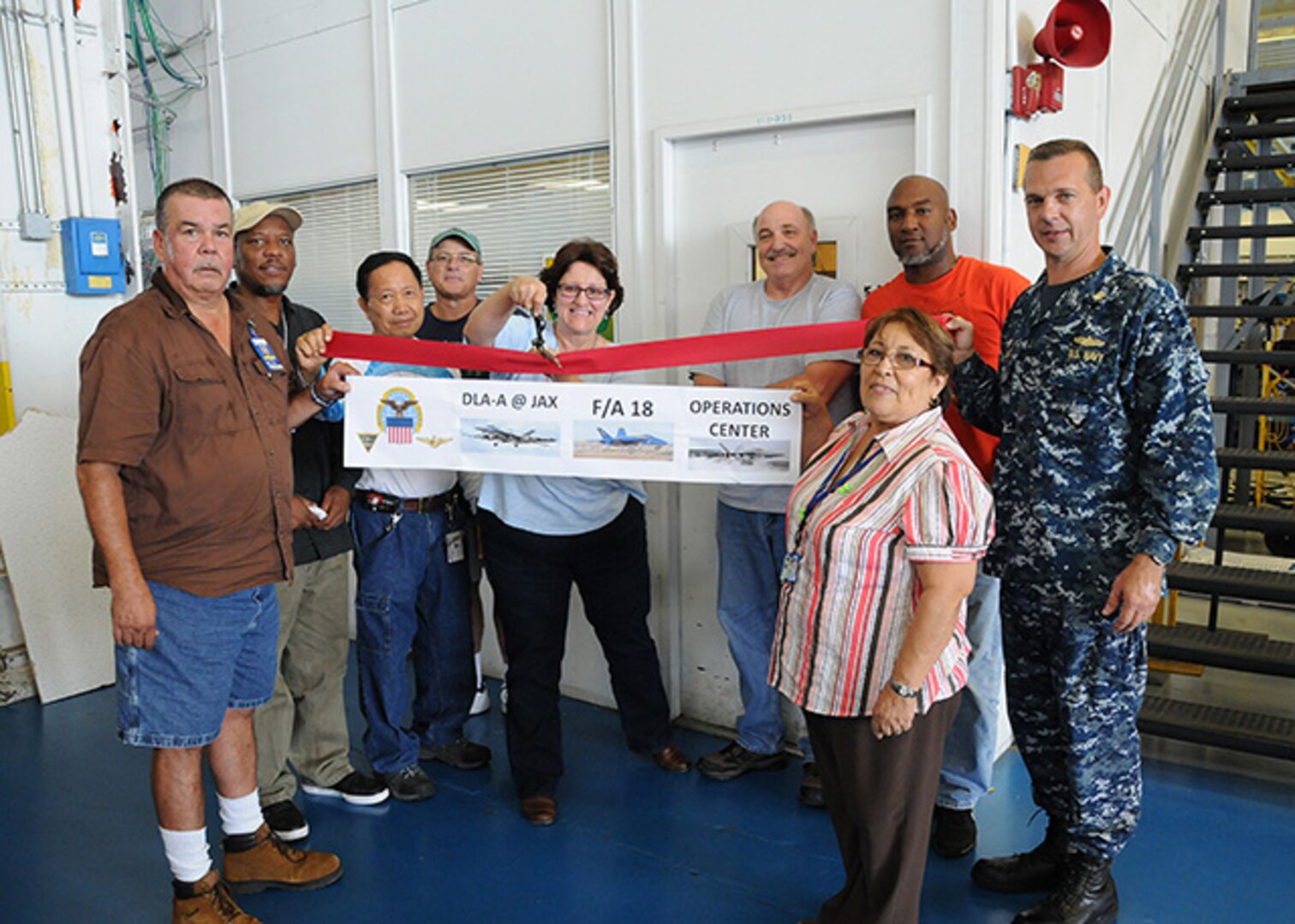 DLA Aviation at Jacksonville Material Management Cell Chief Julie Brewer cuts the ribbon Nov. 2 at the reopening of the newly renovated F/A 18 Material Support Office on Fleet Readiness Center Southeast, Jacksonville, Florida. Also pictured are members of DLA Aviation’s F/A 18 Production Support Team and DLA Aviation at Jacksonville Industrial Support Activity Site Commander Navy Commander Maurice Meagher.