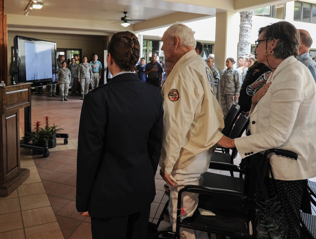 Hickam Field attack survivors and members of Pacific Air Forces stand at attention as the Star Spangled Banner is played as part of a video during a ceremony, Dec. 7, 2015, Joint Base Pearl Harbor-Hickam, Hawaii. The ceremony was held to unveil the new flag case "Old Glory" is to be displayed in. (U.S. Air Force photo by Tech. Sgt. Amanda Dick/Released)