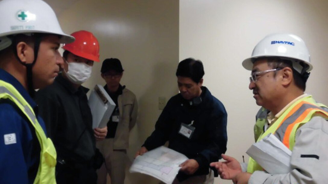Facilities Engineering and Acquisition Division Camp Butler Engineering Technician Hiroshi Shun discusses the fire alarm testing plan for the Division Staff training Facility inspection with members of Marine Corps Base Butler Fire Alarm Shop and American Engineering Corporation Dec. 4.