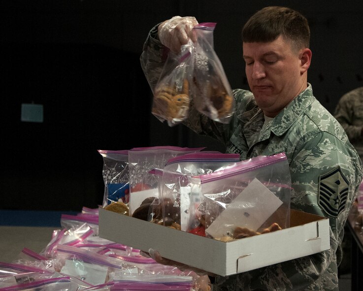 Master Sgt. Jeremy Britten, 620th Ground Combat Training Squadron first sergeant, organizes bags of cookies into boxes Dec. 7, 2015, inside the Fall Hall Community Center on F.E. Warren Air Force Base, Wyo. Each bag was delivered to the rooms of Airmen living in the dorms. (U.S. Air Force photo by Senior Airman Brandon Valle)
