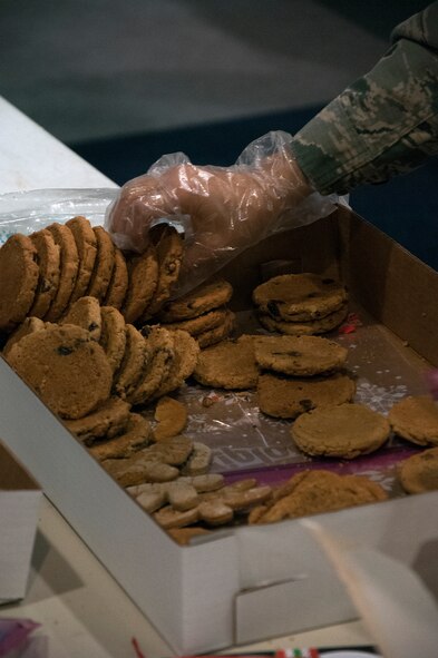 A volunteer picks up a few cookies to make a cookie bag for Airmen living in the dorms Dec. 7, 2015, inside the Fall Hall Community Center on F.E. Warren Air Force Base, Wyo. More than 6,000 cookies were donated by the Air Force Association and others for the cookie bags. (U.S. Air Force photo by Senior Airman Brandon Valle)