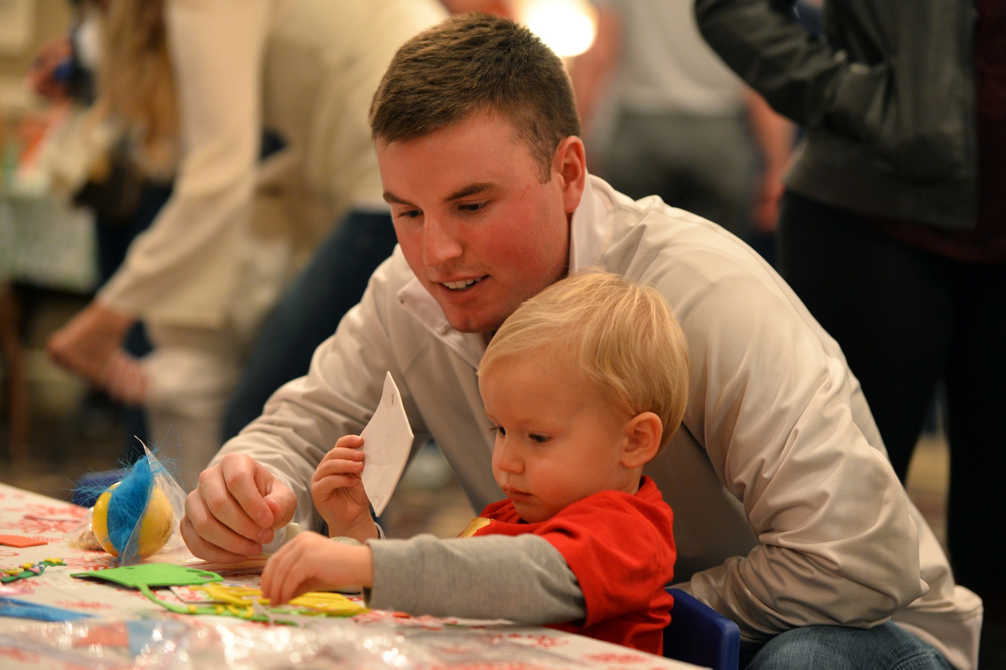 U.S. Air Force Airman 1st Class Kyle Gee, with the 55th Comptroller Squadron, decorated Christmas trees with his two-year-old son, Brady, at the Christmas Tree Celebration held at the Patriot Club on Dec. 3, Offutt Air Force Base, Neb.  Hundreds of families attend the annual event.  (U.S. Air Force photo by Josh Plueger/Released)