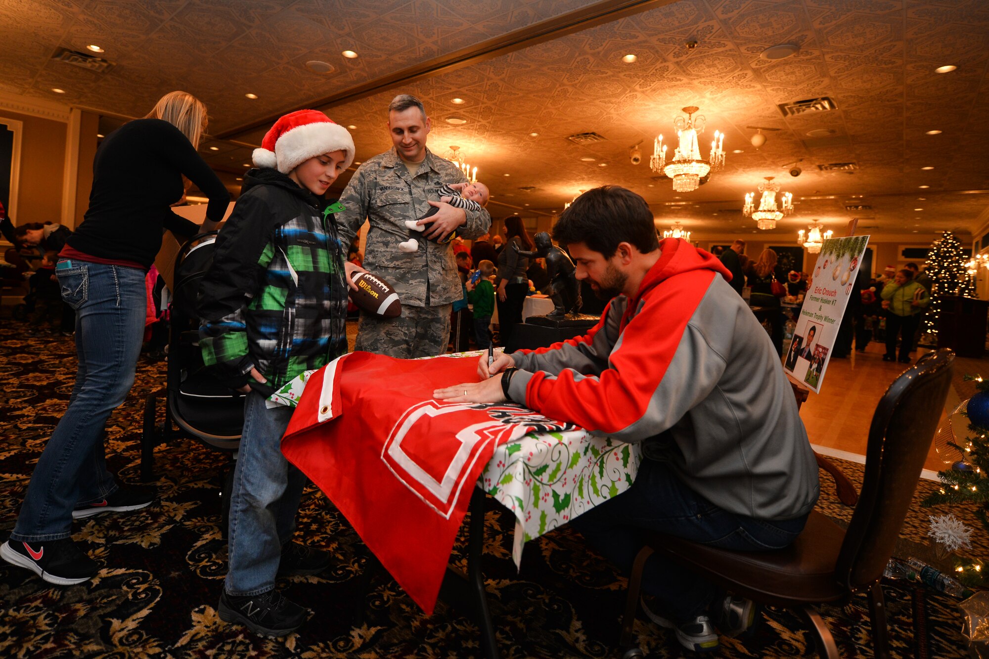 Devin Vandersnick, 11, gets an autograph from former Nebraska Cornhusker and Heisman winning quarterback Eric Crouch while attending the annual Christmas Tree Lighting ceremony held at the Patriot Club on Dec. 3, Offutt Air Force Base, Neb.  Crouch brought the prestigious trophy for attendees to look at.  (U.S. Air Force photo by Josh Plueger/Released)