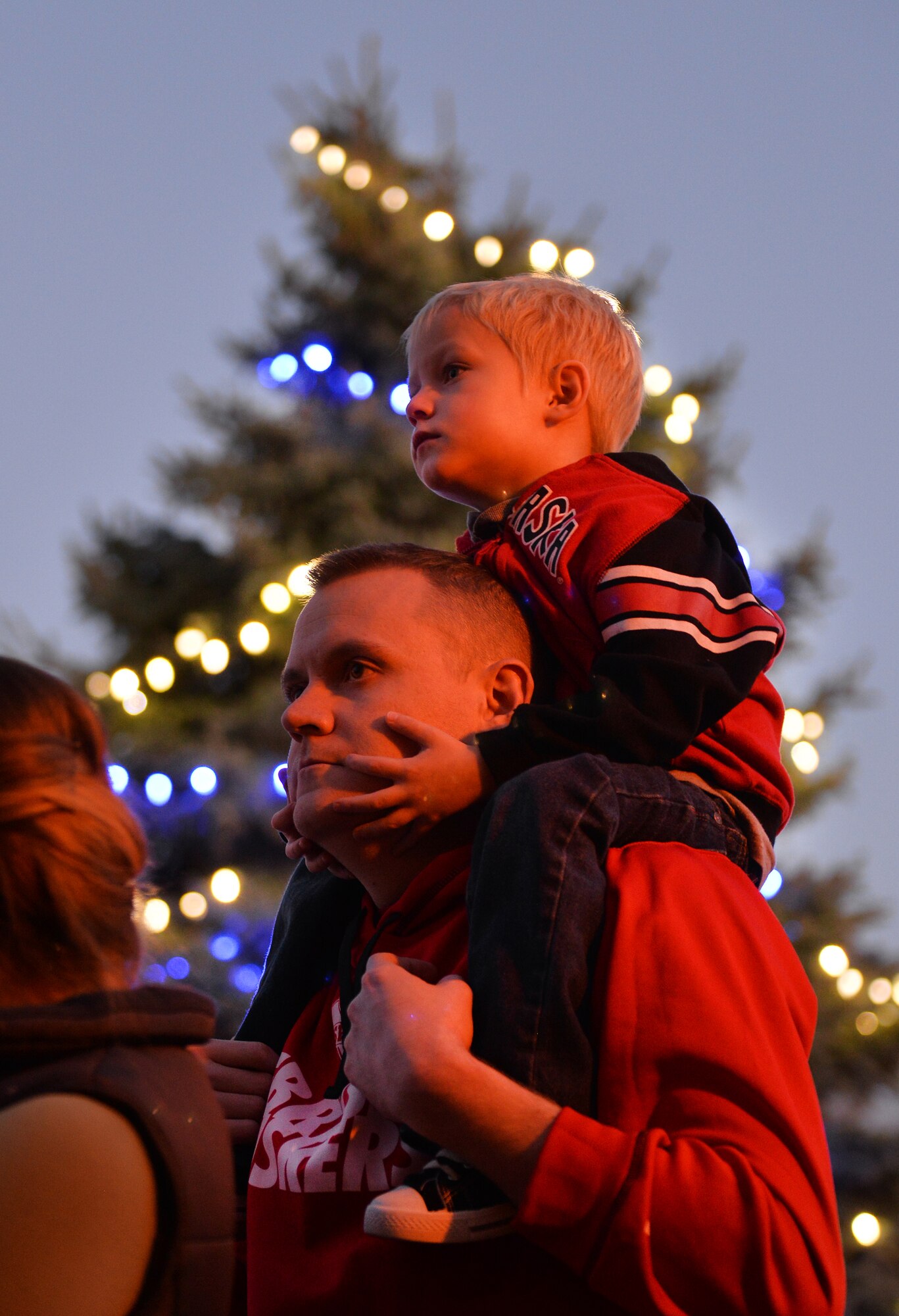 U.S. Air Force Staff Sgt. Trent Carey, assigned to United States Strategic Command, hold his four-year-old son, Karsen, on his shoulders while they wait to enter the Patriot Club for the annual Christmas Tree Lighting Ceremony held Dec. 3, Offutt Air Force Base, Neb.  Special guests included Heisman Trophy winner Eric Crouch of the University of Nebraska, as well as Miss Nebraska Alyssa Howell.  (U.S. Air Force photo by Josh Plueger/Released)
