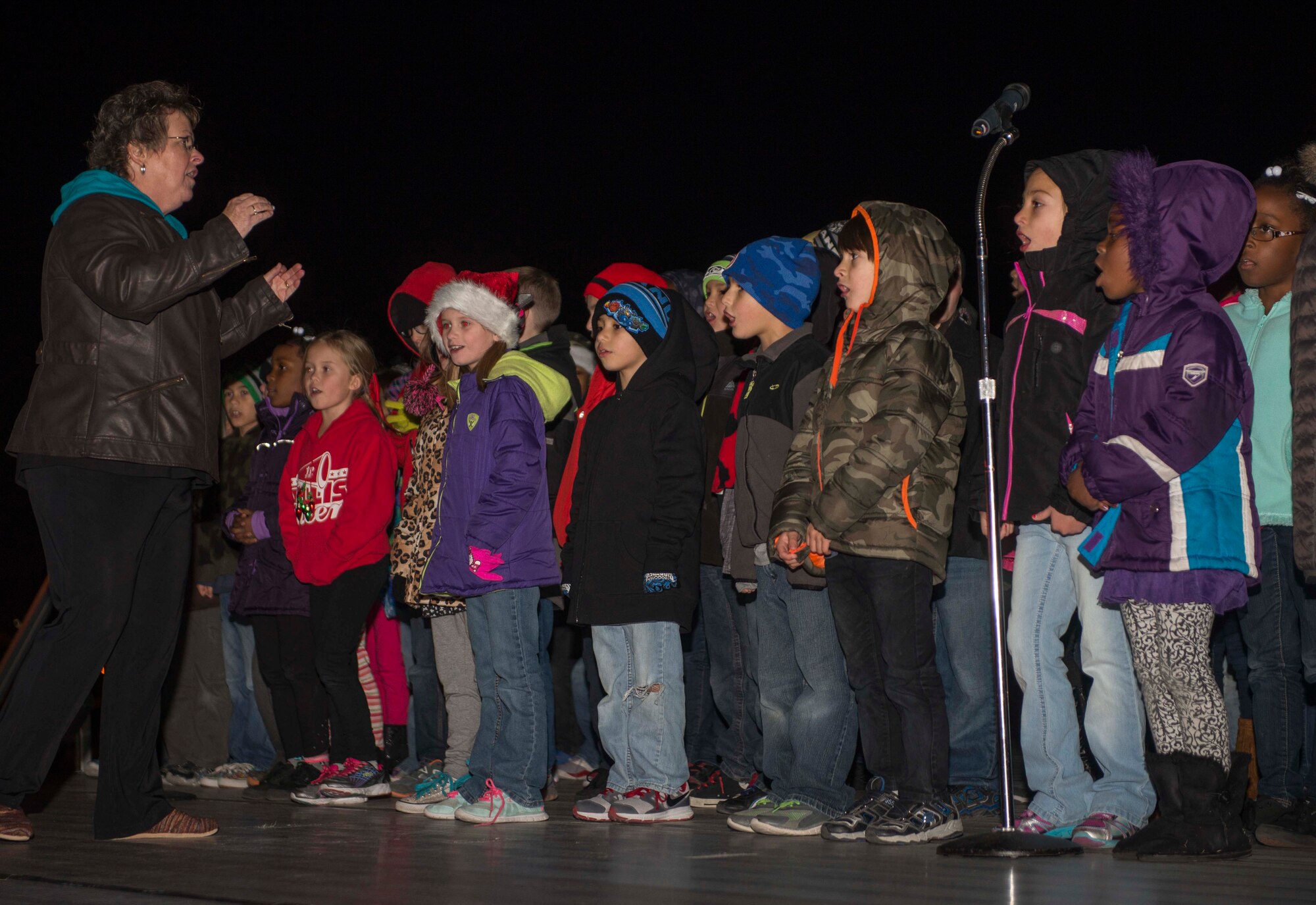 Lynn Pomke, Holloman Elementary School music director, leads the Holloman Elementary School Choir in singing Christmas-themed songs at the Lighting of the Christmas Tree and Menorah Ceremony on Dec. 1. The children sang “Jingle All the Way,” “Silent Night” and “Dreidel, Dreidel, Dreidel” in celebration of the holiday season. (U.S. Air Force photo by Airman 1st Class Randahl J. Jenson)   