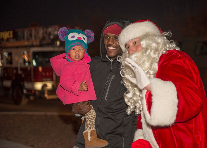 Zeah and her father, Saquawn Figaro, pose for a photo with Santa during the Lighting of the Christmas Tree and Menorah Ceremony in the Base Exchange parking lot Dec. 1. Santa rode into the BX parking lot on a firetruck to say hello to everyone gathered. (U.S. Air Force photo by Airman 1st Class Randahl J. Jenson) 