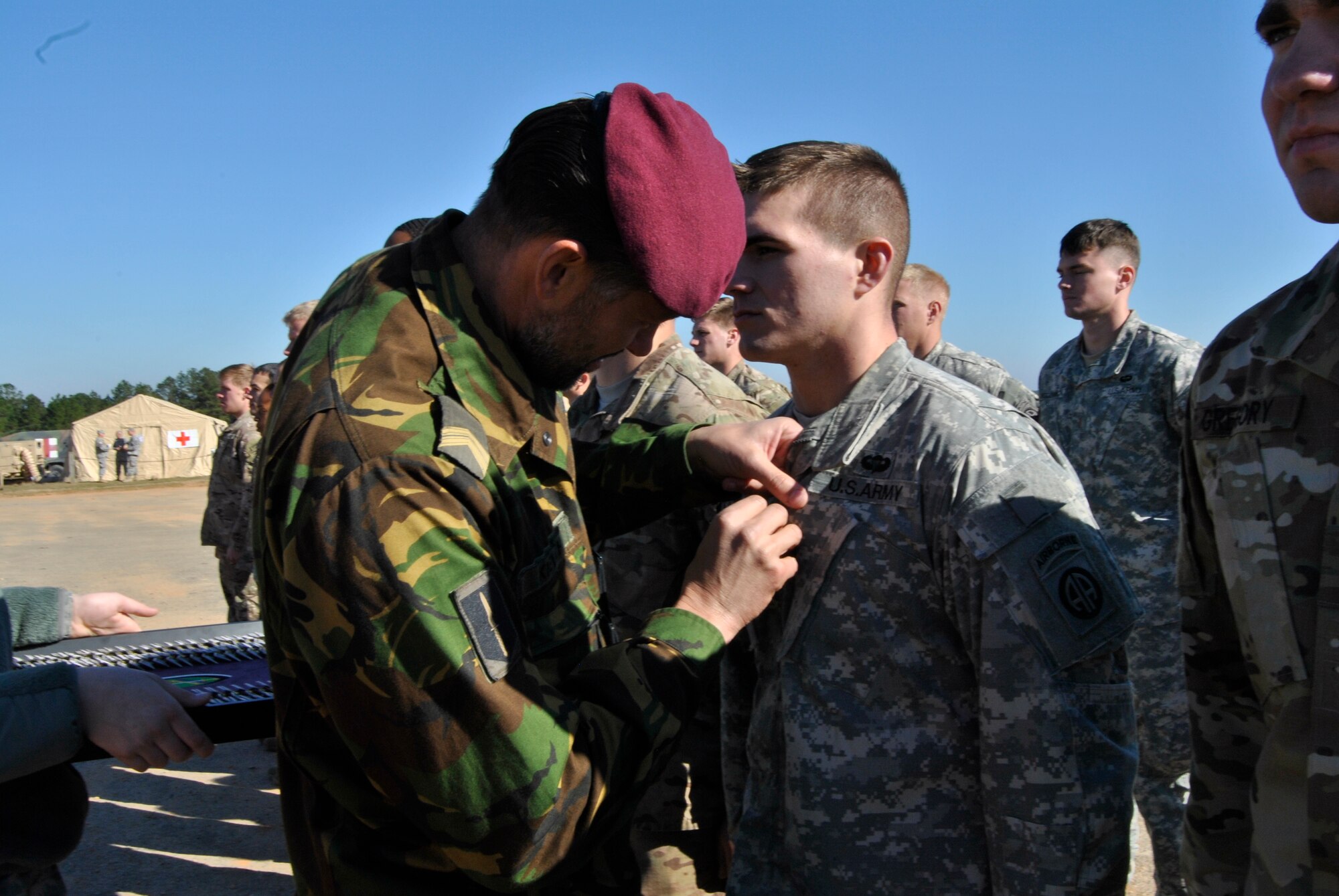 A Netherlands jumpmaster pins a partner nation wing onto a U.S. Army paratrooper after landing on Sicily Drop Zone during an airborne operation for the 18th Annual Randy Oler Memorial Operation Toy Drop, hosted by U.S. Army Civil Affairs & Psychological Operations Command (Airborne), at Fort Bragg, N.C., Dec. 5, 2015. Operation Toy Drop is the world’s largest combined airborne operation and collective training with seven partner-nation paratroopers participating and allows Soldiers the opportunity to help children in need receive toys for the holidays. (U.S. Army Photo by Spc. Lisa Velazco)