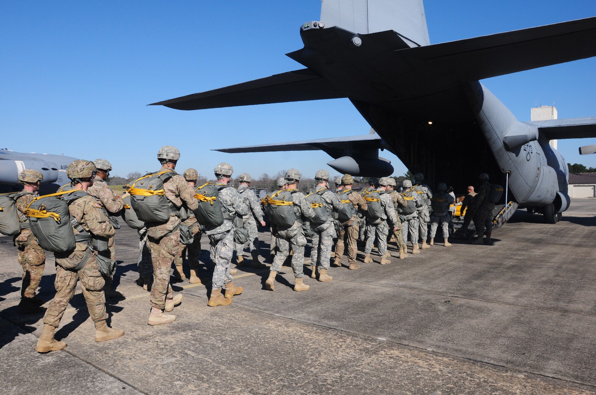 Paratroopers prepare to board a C-130 at the 18th Annual Randy Oler Memorial Operation Toy Drop. The airborne operation was hosted by U.S. Army Civil Affairs & Psychological Operations Command (Airborne), on Dec. 4, 2015, at Pope Field, N.C. Operation Toy Drop is the world’s largest combined airborne operation and collective training exercise with seven partner-nation paratroopers who participated and allowed Soldiers the opportunity to help children in need receive toys for the holidays. (U.S. Army photo by Sgt. Nicole Paese)