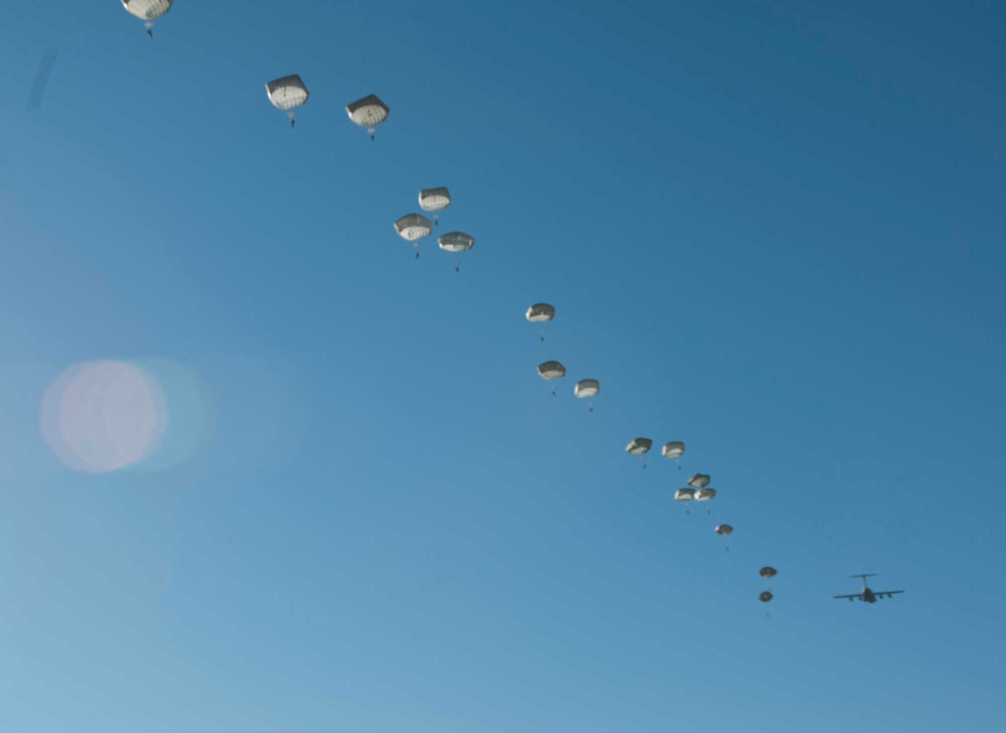 Paratroopers exit a C-130 aircraft during a static line jump at Sicily Drop Zone for the 18th Annual Randy Oler Memorial Operation Toy Drop, hosted by U.S. Army Civil Affairs & Psychological Operations Command (Airborne), Dec. 4, 2015 at Fort Bragg, N.C. This event is the world’s largest combined airborne operation and collective training exercise with seven partner-nation paratroopers who participated and allowed Soldiers the opportunity to help children in need receive toys for the holidays. (U.S. Army photo by Staff Sgt. Shaiyla Hakeem)