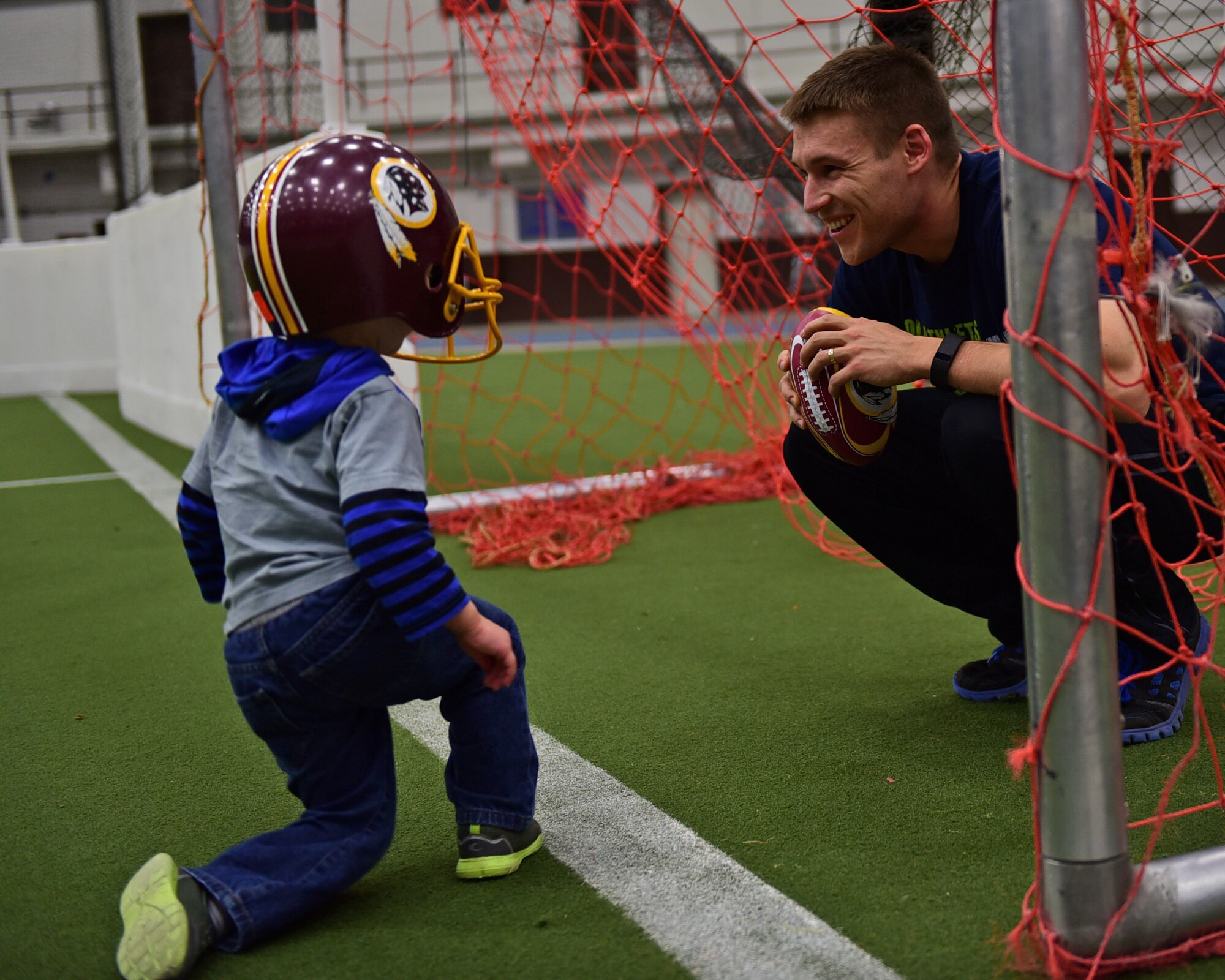 Staff Sgt. Chris Meyer, 28th Contracting Squadron contract administrator, celebrates a touchdown with his son, Nate, while playing football in the Pride Hangar at Ellsworth Air Force Base, S.D., Nov. 4, 2015. Meyer and his family use the facility during winter months to escape inclement weather. (U.S. Air Force photo by Airman 1st Class James L. Miller/Released) 