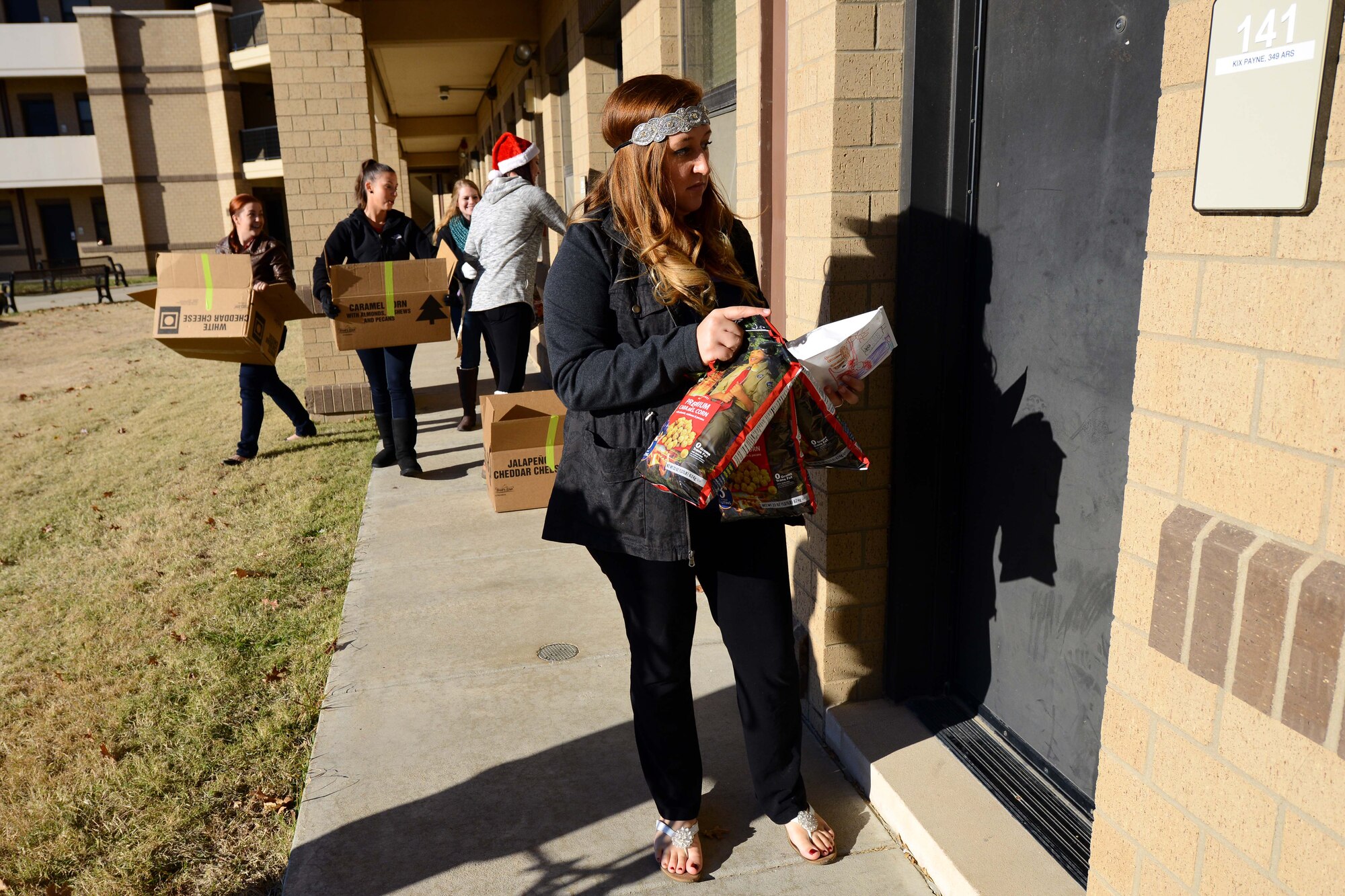 Giavanna Woods, McConnell Officers’ Spouses’ Club president, goes door-to-door around the dorms handing out bags of cookies, Dec. 4, 2015, at McConnell Air Force Base, Kan. McConnell spouses collected and distributed thousands of cookies to Airmen and offices in an effort to spread holiday cheer. (U.S. Air Force photo/Airman 1st Class Christopher Thornbury)