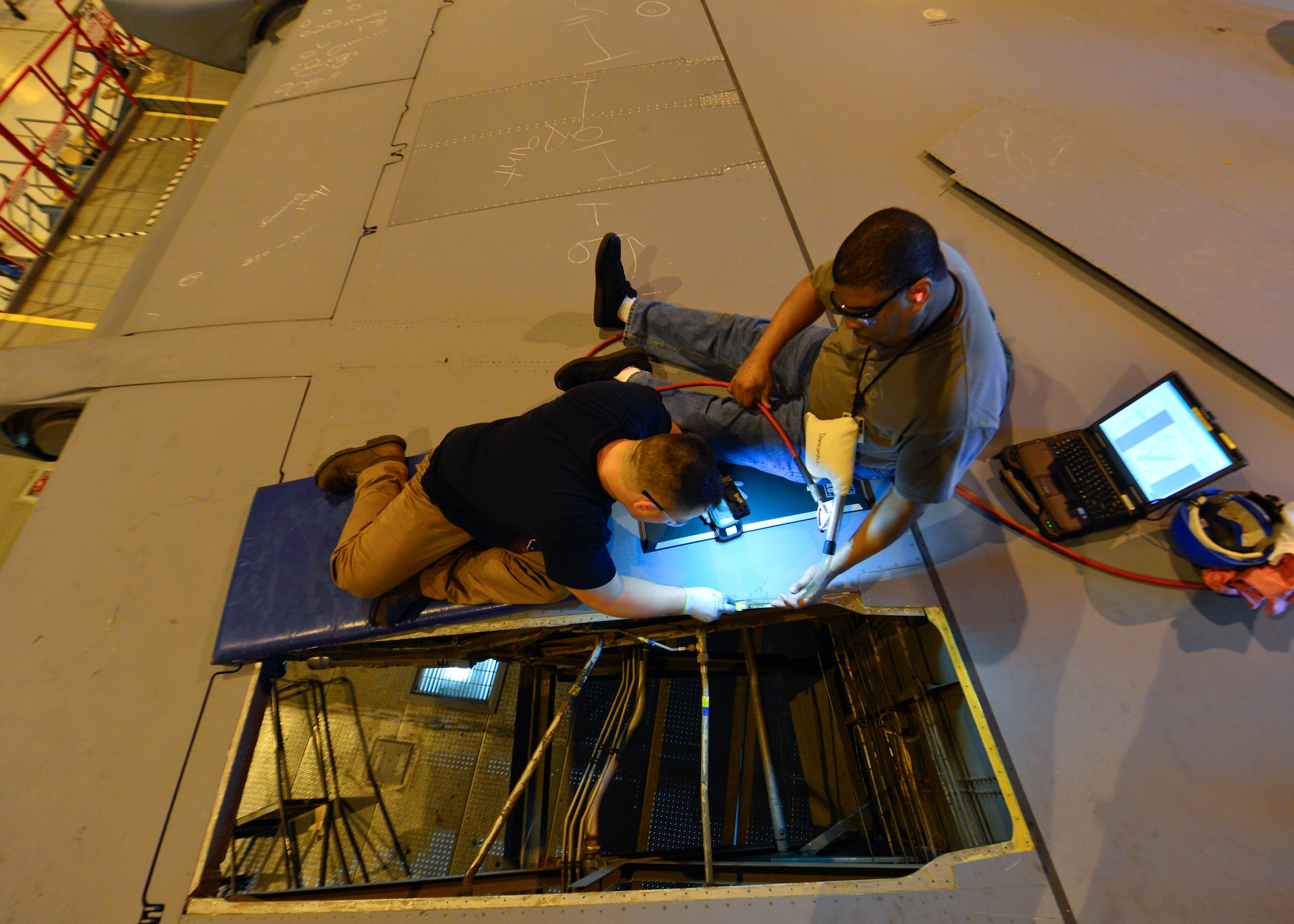 Mike Kuberski, left, and John Luke, right, both 436th Maintenance Squadron sheet metal mechanics, scrape sealant off of a trailing edge panel from a C-5M Super Galaxy wing during a Maintenance Steering Group-3 Major inspection Dec. 2, 2015, in the isochronal dock at Dover Air Force Base, Del. The new panel was installed and resealed during the inspection. (U.S. Air Force photo/Senior Airman William Johnson)