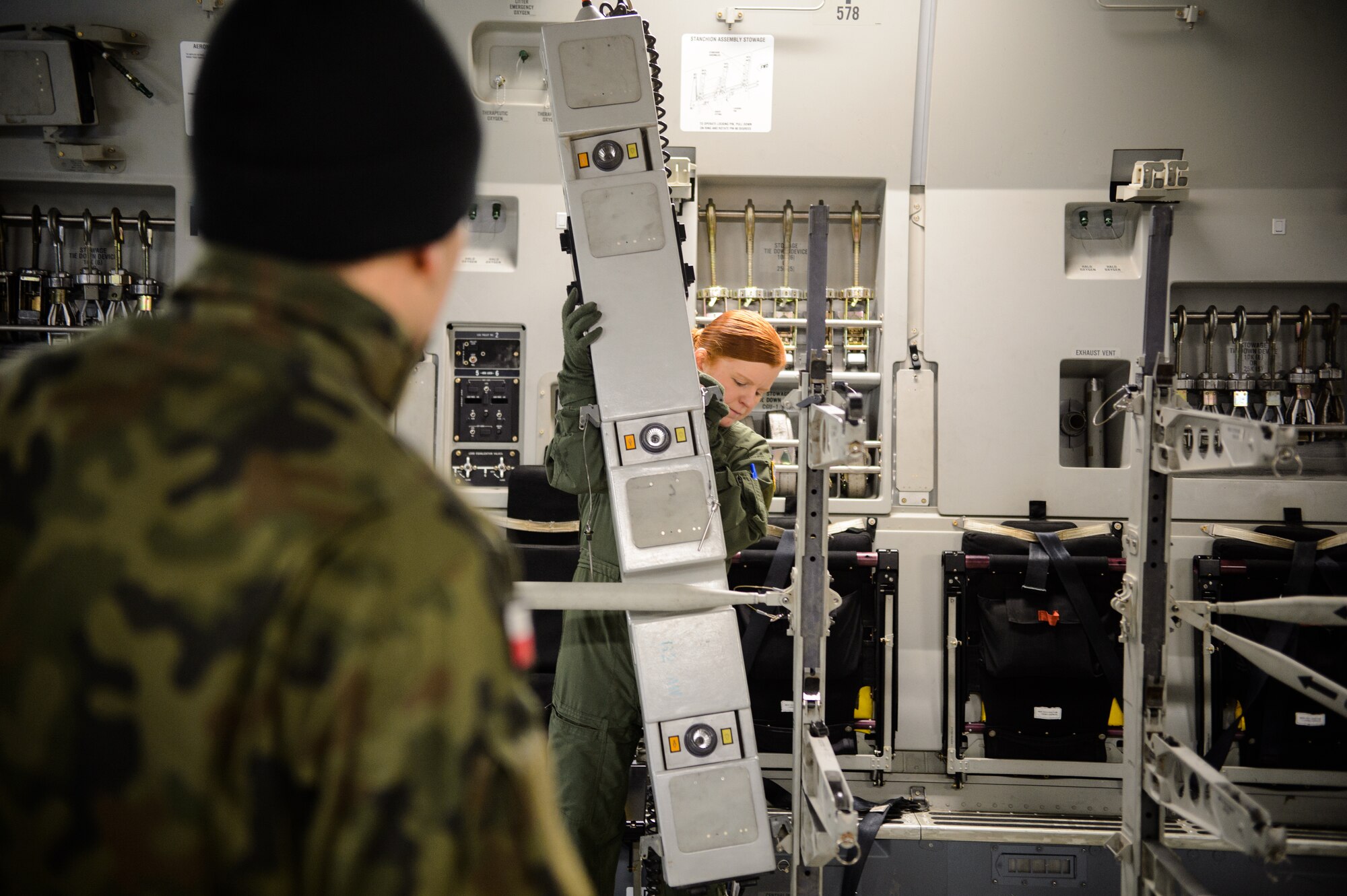U.S. Air Force Staff Sgt. Michelle Burns, 86th Aeromedical Evacuation Squadron technician, configures a C-17 Globemaster III as a Polish aeromedical evacuation doctor watches Dec. 3, 2015, at Ramstein Air Base, Germany. Burn and the 86th AES conducted a mock mission for the Polish aeromedical evacuation team in order to share knowledge with each other. (U.S. Air Force photo/Staff Sgt. Armando A. Schwier-Morales)