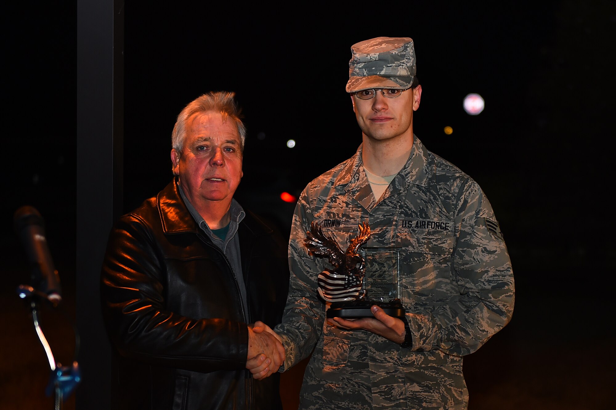 Senior Airman Christopher Orwin, 460th Operations Group Detachment 45 satellite operations technician, receives the Kristopher Mansfield award from Craig Mansfield during a tree-lighting ceremony Dec. 3, 2015, on Buckley Air Force Base, Colo. The ceremony takes place every year to honor Senior Airman Kristopher Mansfield, who was killed in a drunk driving accident in 2004. (U.S. Air Force photo by Airman First Class Gabrielle Spradling/Released)