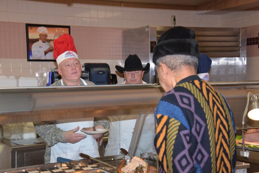 Maj. Gen. Scott Jansson (left), Air Force Nuclear Weapons Center, serves a Thanksgiving  meal at Thunderbird Inn dining facility on Thanksgiving Day. Commanders, chiefs, first sergeants and their spouses served the meal as part of an annual tradition where senior leaders serve a Thanksgiving meal at the facility. (Photo by Dennis Carlson)