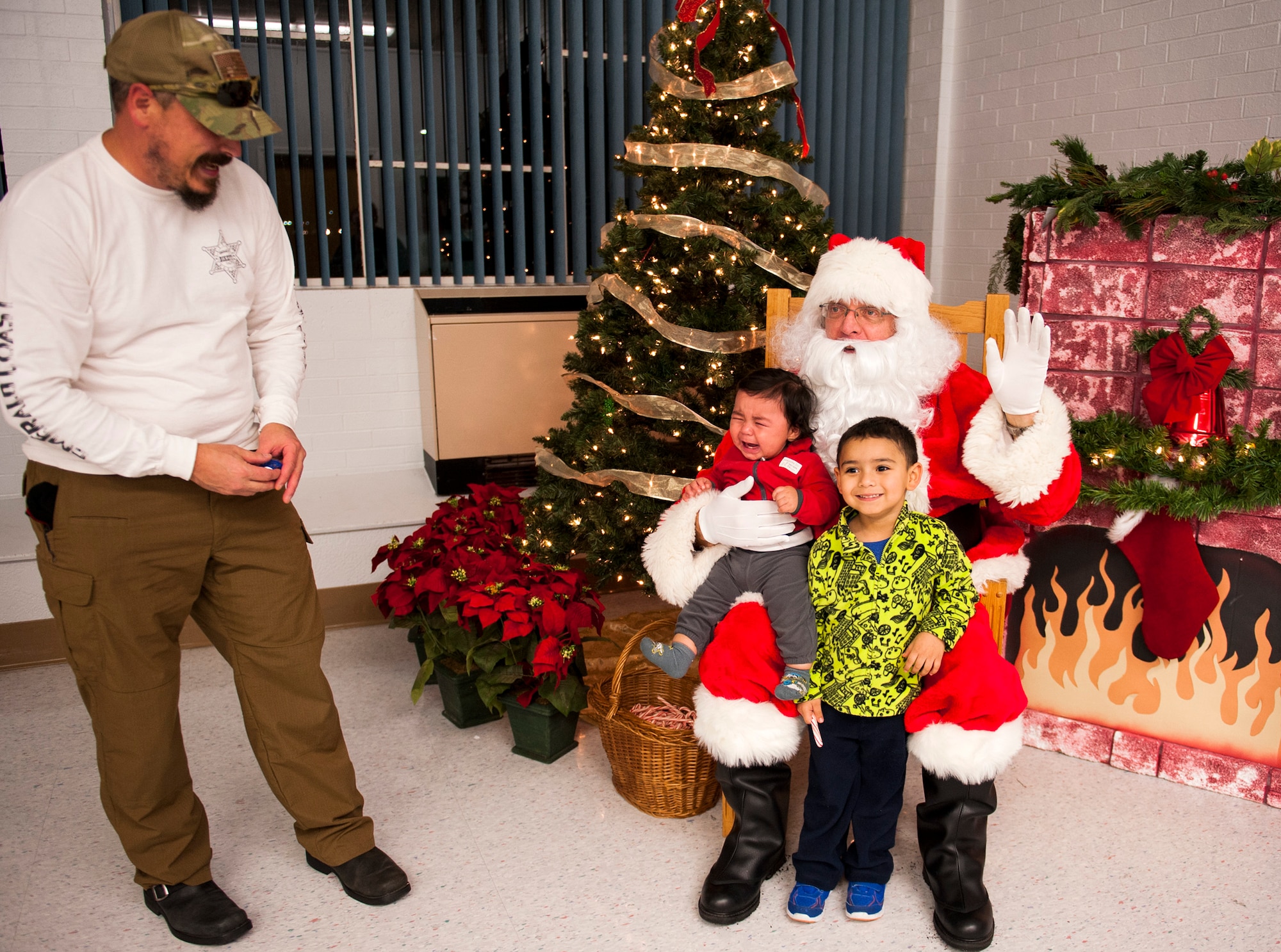 Byron Hewett, looks on as sons, Brayden, 7-months-old, and Bryson, 4-years-old, visit with Santa during the Christmas tree lighting festivities Dec. 4 at Eglin Air Force Base, Fla. The Eglin community came out for the tree lighting, the announcement of base Christmas card contest winners, and the Chapel’s reception. (U.S. Air Force photo/Ilka Cole)