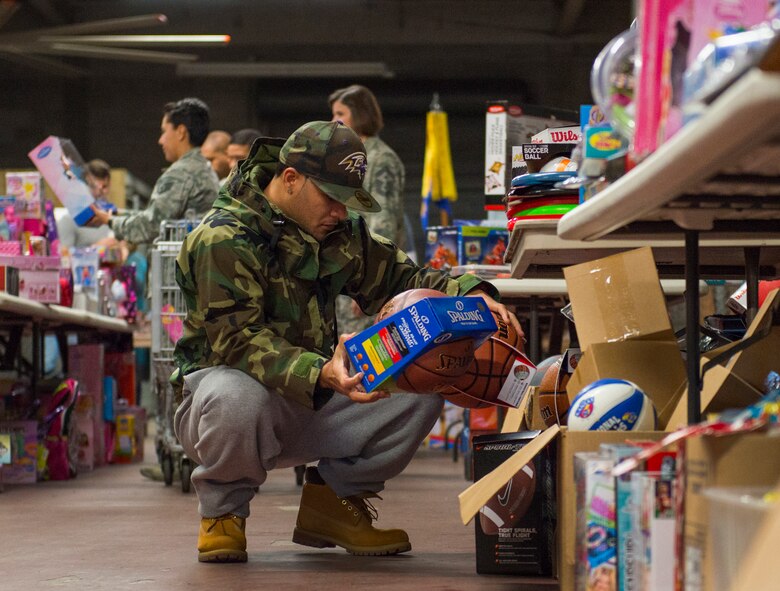 A family member evaluates the basketballs and other sports equipment available during the annual holiday toy distribution at Eglin Air Force Base, Fla., Dec. 4.  Approximately 2,000 toys were collected by donations made throughout the year. Toys, bikes, books, games, crafts, sports equipment and stuffed animals were given to active-military families in need of assistance during the holidays.  (U.S. Air Force photo/Samuel King Jr.)
