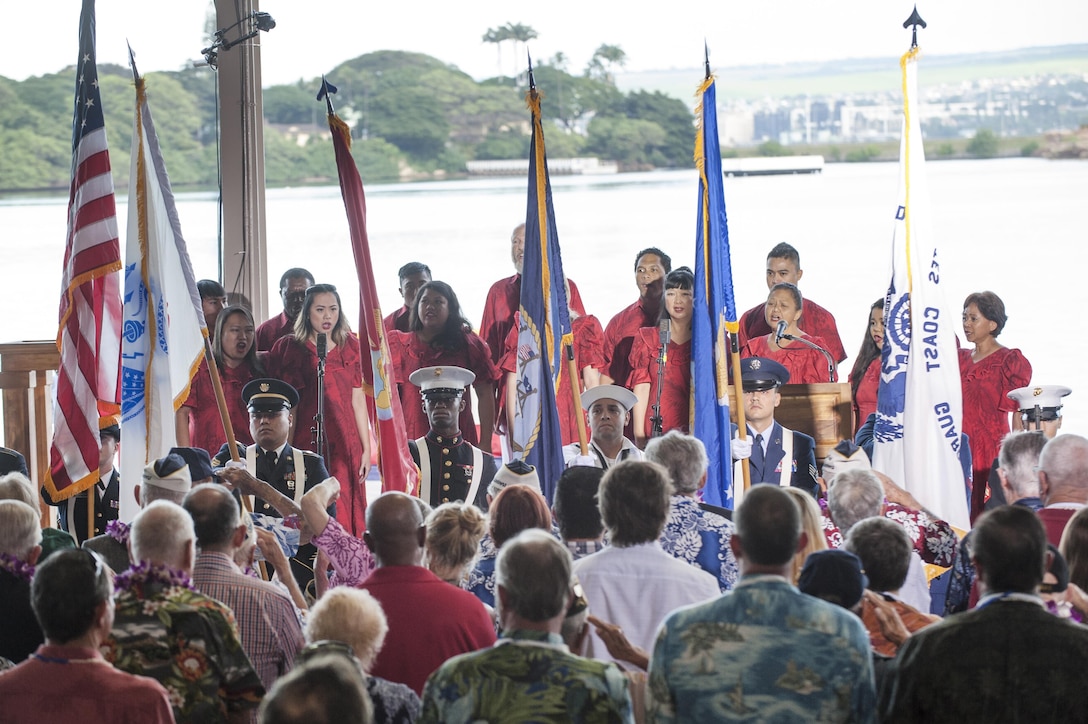 Members of U.S. Pacific Command's joint service color guard present the colors as Melamai Kapu’uwaimai Choir members sing the national anthem during the Pearl Harbor Day Commemoration Anniversary at Joint Base Pearl Harbor-Hickam, Hawaii, Dec. 7, 2015. U.S. Air Force photo by Staff Sgt. Christopher Hubenthal