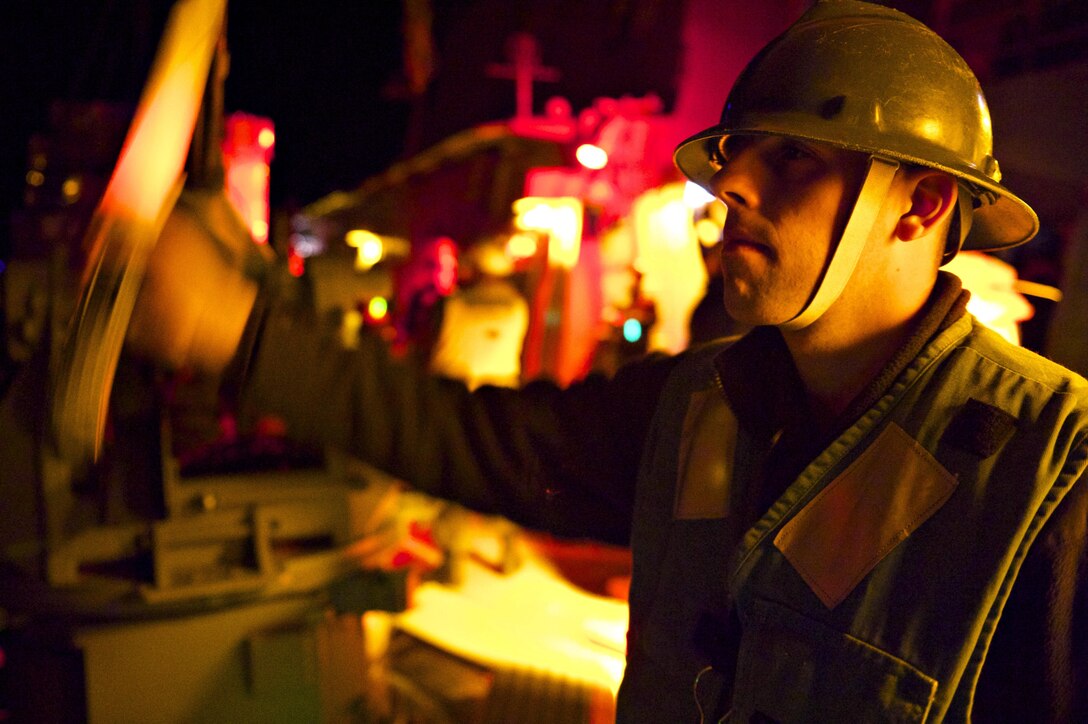 U.S. Navy Seaman Anthony Fabiochi signals the Military Sealift Command fleet replenishment oiler USNS Leroy Grumman for more cargo during a replenishment at sea with the USS Carney, an Arleigh Burke-class guided missile destroyer, in the Mediterranean Sea, Dec. 7, 2015. Fabiochi is a boatswain’s mate. The Carney is conducting a routine patrol in the U. S. 6th Fleet area of operations to support U.S. national security interests in Europe. U.S. Navy photo by Petty Officer 1st Class Theron J. Godbold