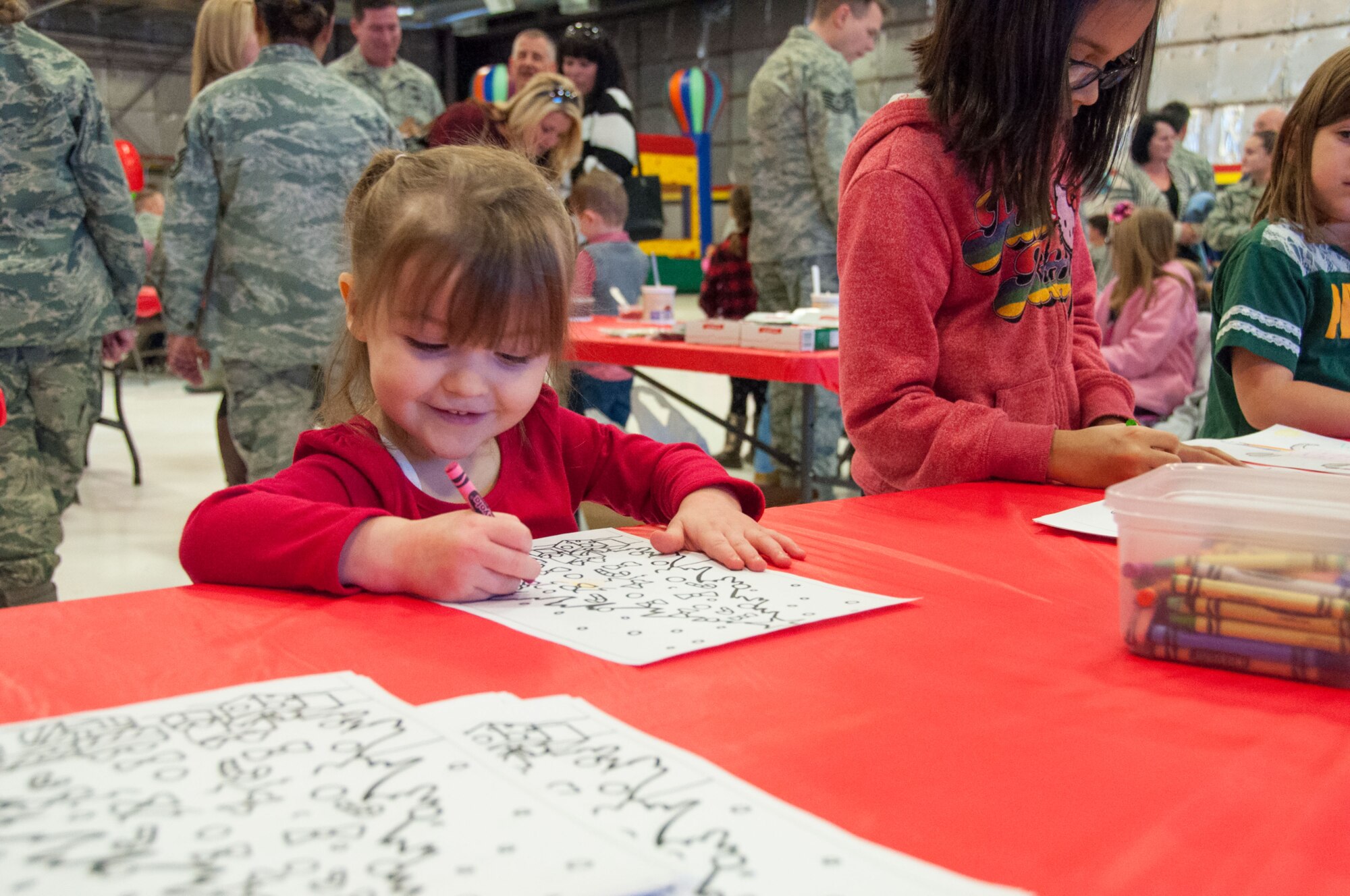 Annaka Morgan passes time with a coloring book while awaiting the arrival of Santa Claus at a 419th Fighter Wing holiday party today. Claus traveled pilot-style in an F-16 to deliver some early Christmas gifts to nearly 300 kids of 419 FW reservists