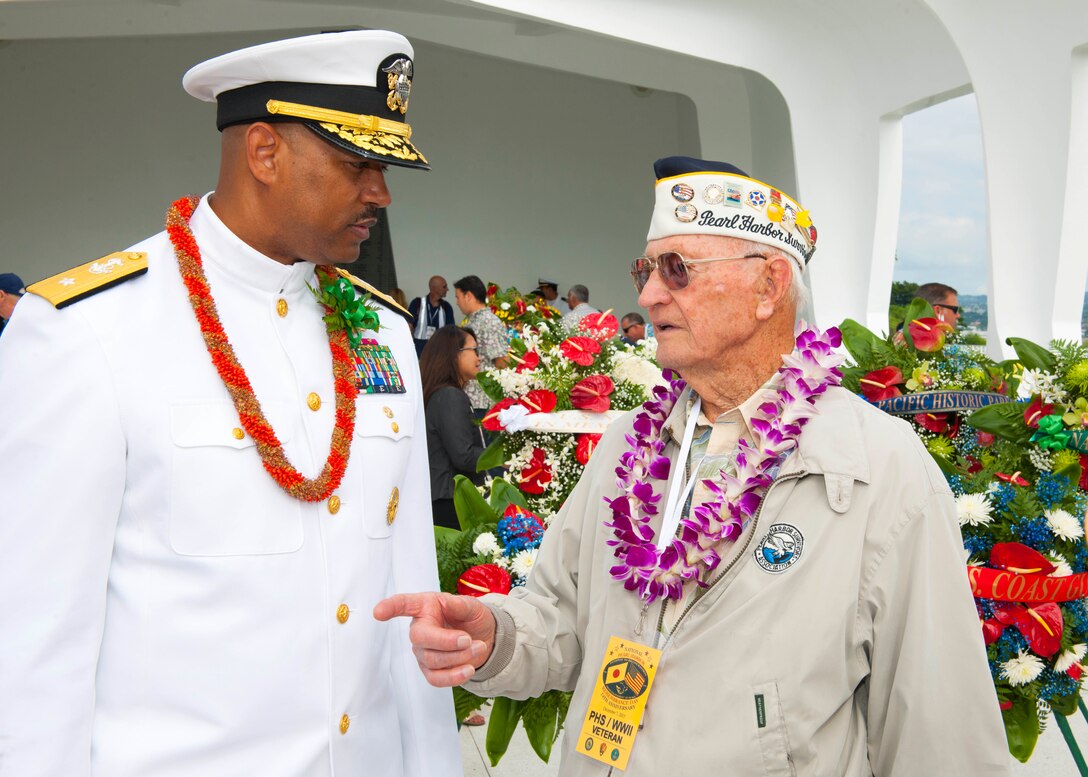 Navy Rear Adm. John Fuller, left, commander, Navy Region Hawaii and Naval Surface Group Middle Pacific, speaks with Ed Schuler, a survivor of the attacks on Pearl Harbor during a wreath dedication ceremony on Joint Base Pearl Harbor-Hickam, Hawaii, Dec. 7, 2015. U.S. Navy photo by Petty Officer 2nd Class Jeff Troutman