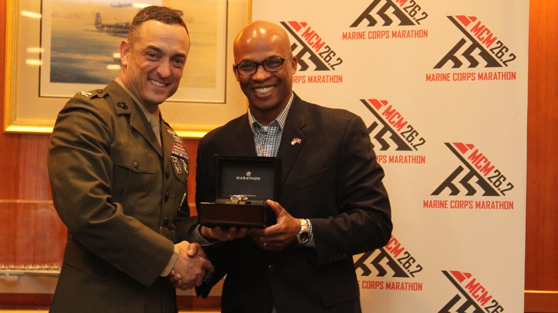 Col. Joseph M. Murray the commanding officer of Marine Corps Base Quantico (left) presents Maj. Tracey Holtshirley a runner in the Marine Corps Marathon, the 1775 award during the Marine Corps Marathon awards ceremony at the United States Navy Memorial Dec. 4, 2015. Holtshirley was the 1775th Marine to finish the 40th MCM Oct. 25, 2015.