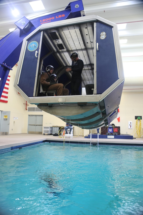 Students prepare to be lowered into the pool in the helicopter dunker aboard Aviation Water Survival Training Center aboard Marine Corps Air Station Miramar, Calif., Dec. 3. Aviation Water Survival Training is hosted every week, twice a week, and is mandatory for all pilots every four years. (U.S. Marine Corps Photo by Lance Cpl. Harley Robinson/Released)