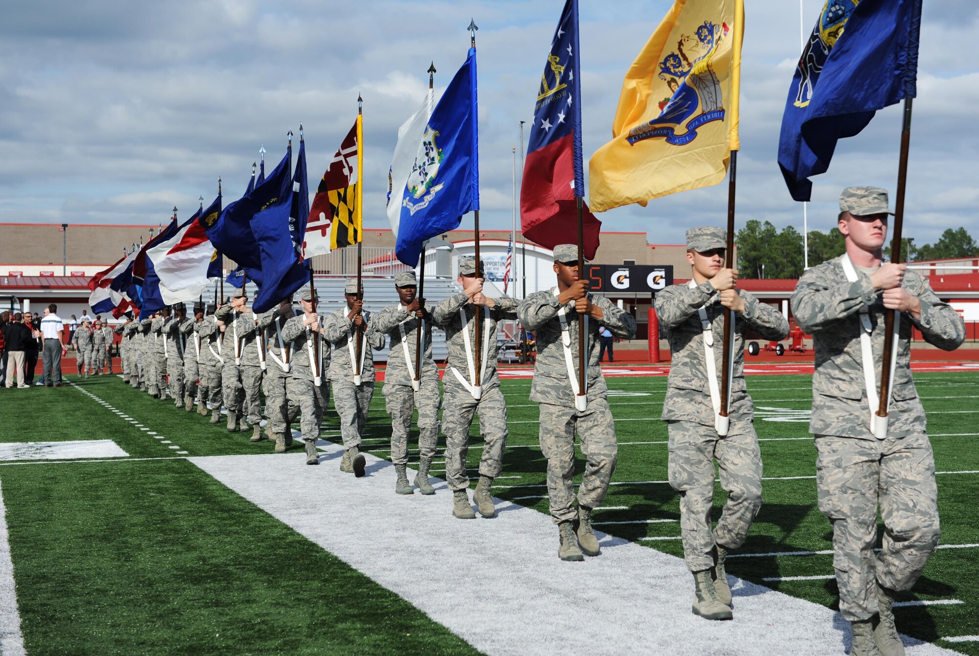 Airmen from the 81st Training Group, Keesler Air Force Base, Miss., line up along the Biloxi High School Football Stadium field while carrying the 50-state flags during the 2015 Mississippi Bowl Dec. 6, 2015. Col. Dennis Scarborough, 81st Training Wing vice commander, the National Anthem singer and the Keesler Honor Guard also participated in the pre-game celebration. (U.S. Air Force photo by Kemberly Groue)