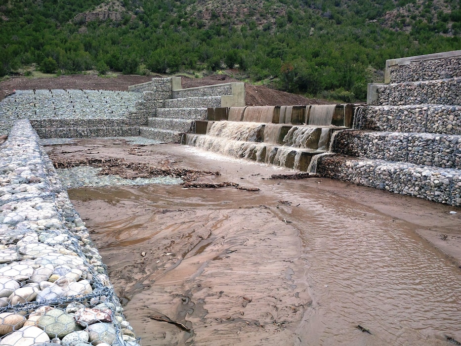 SANTA CLARA PUEBLO, N.M. – Water flows over the partially-constructed “structure 2” July 30, 2015.  The structure is part of the advanced measures the District is building to help protect the Pueblo from flash flooding. Photo by Mike Goodrich. 
