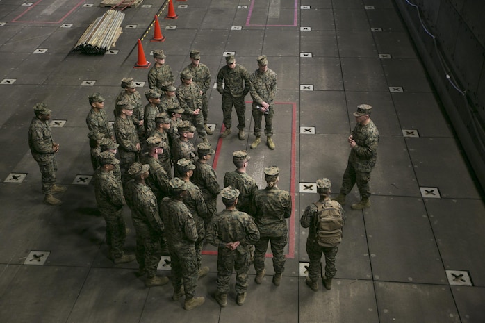 Master Sgt. Charles Garcia, Marine Aircraft Group 12 logistics chief, explains to his Marines the different parts of a ship and what they are used for during a site survey of the USS Bonhomme Richard at U.S. Fleet Activities Sasebo, Dec. 4, 2015. Garcia executed the survey to confirm everything was secure and large enough for Marine Attack Squadron 214 AV-8B harriers to land on safely.