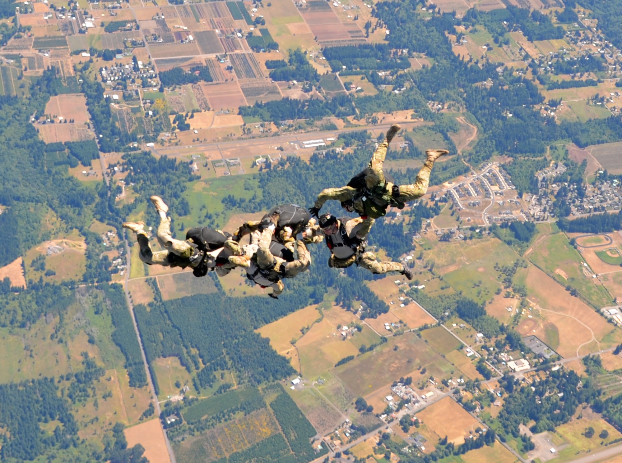 Pararescuemen from the 304th Rescue Squadron, Portland International Airport, Oregon, jump from an HC-130 P/N King over Beaver Oaks, Oregon, July 27, 2013. Combat rescue officers and PJs go through the same initial training pipeline before joining a search and rescue unit.