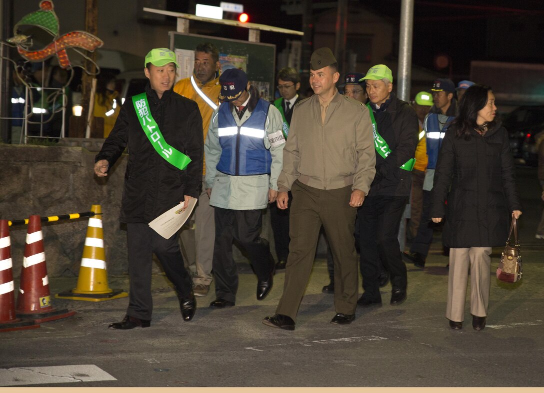 Yoshihiko Fukuda, mayor of Iwakuni, Lt. Col. Gary Thomason, executive officer of Marine Corps Air Station Iwakuni, Japan, and other city officials step on for the Sixth Joint Leadership Walk in Iwakuni Dec. 4, 2015. The joint leadership walk represents the unique and enduring relationship between the air station and Iwakuni City. Throughout the walk, Fukuda and Thomason stepped into various community establishments to converse with the owners and patrons.