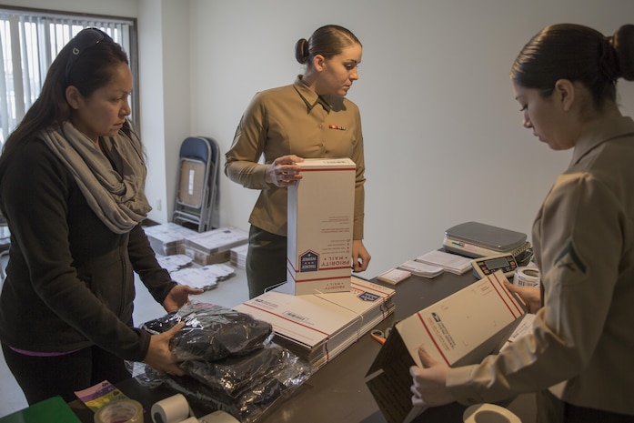 Maribell Martinez, left, a station resident, sends packages at Row Home 9148 A, one of the various mobile post office locations being manned by Lance Cpl. Natalie Mullin, middle, and Lance Cpl. Sara Garciamedina, right, postal clerks with Headquarters and Headquarters Squadron, at Marine Corps Air Station Iwakuni, Japan, Dec. 4, 2015. Throughout the week, one mobile location will be opened daily and manned by postal Marines that can offer assistance if needed. The postal express are mobile locations that offer opportunities for station residents to drop-off holiday mail while also meeting the U.S. postal service mailing deadlines.