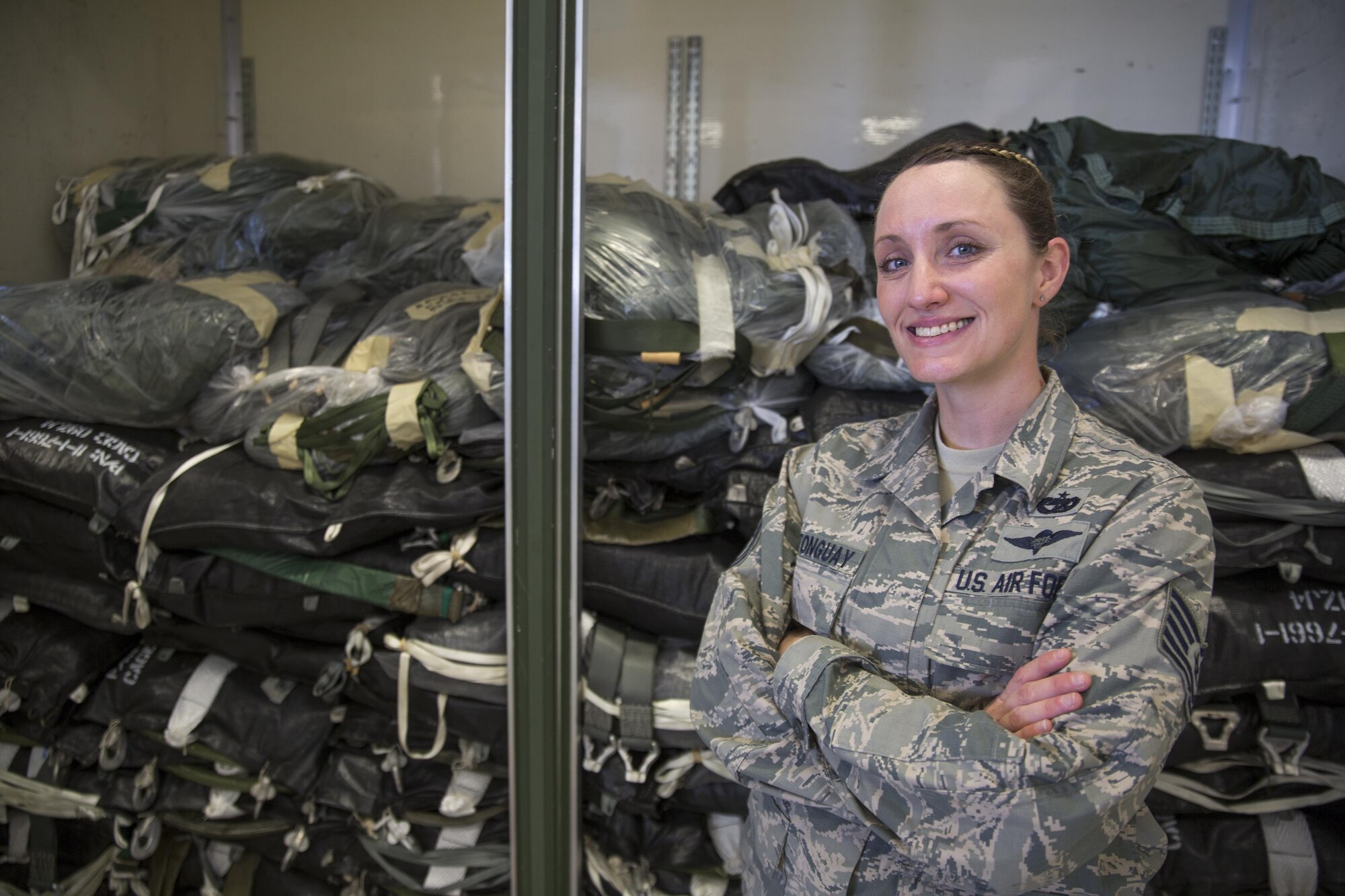Tech. Sgt. Chasity Castonguay, 374th Logistics Readiness Squadron rigger operations supervisor, shows over 100 parachutes ready to use for low-cost low altitude airdrops during Operation Christmas Drop at Andersen Air Force Base, Dec. 5, 2015. The T-10 and T-10R parachutes were donated by the U.S. Army; utilizing repurposed, expired personnel chutes for cargo airdrop is just one way LCLA airdrops are cost-efficient and easy to apply across the global airlift community. The 40,000 pounds of donated items are packed into bundles for C-130 aircrews from USAF, JASDF, and RAAF to perform LCLA airdrops on unsurveyed drop zones while providing critical supplies to 56 islands throughout the Commonwealth of the Northern Marianas, Federated States of Micronesia and Republic of Palau. (U.S. Air Force photo by Osakabe Yasuo/Released)