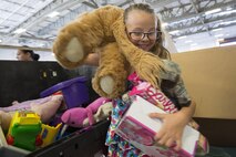 A volunteer carries toys to place inside a box while sorting donations for Operation Christmas Drop at Andersen Air Force Base, Guam, Dec. 5, 2015. Toys are a rarity in the remote islands of the Pacific, so sorting them ensures each island receives their fair share of the donations. (U.S. Air Force photo by Osakabe Yasuo/Released)