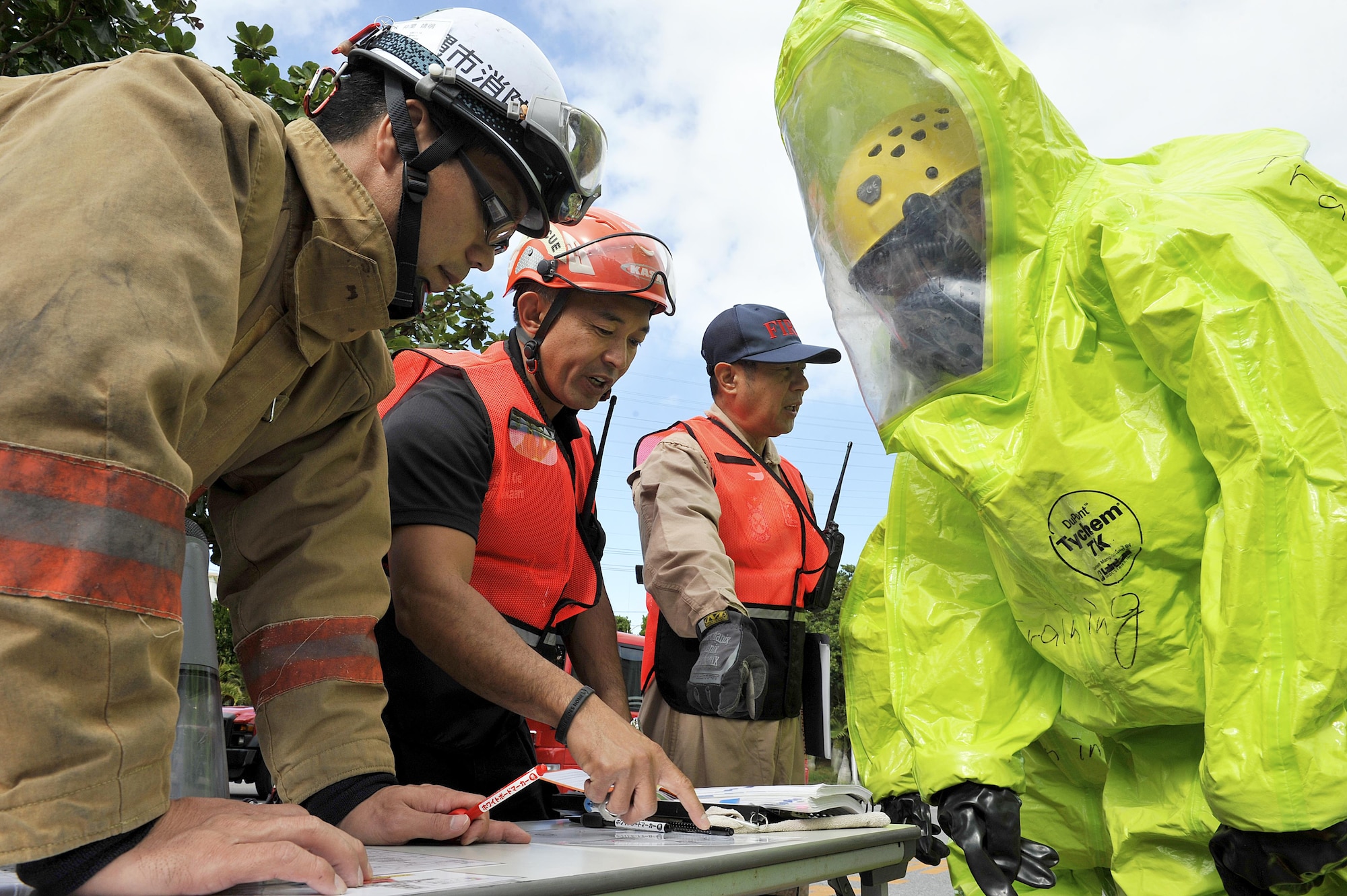 Yuji Nakayama, 18th Civil Engineer Squadron district chief, provides instructions to Kadena fire crew members during a bilateral hazardous materials training exercise, Dec. 8, 2015, at the Okinawa City Civic Center, Japan. Bilateral training exercises allow Kadena and local fire department personnel to further understand each other's skills and foster a better working relationship. (U.S. Air Force photo by Naoto Anazawa)