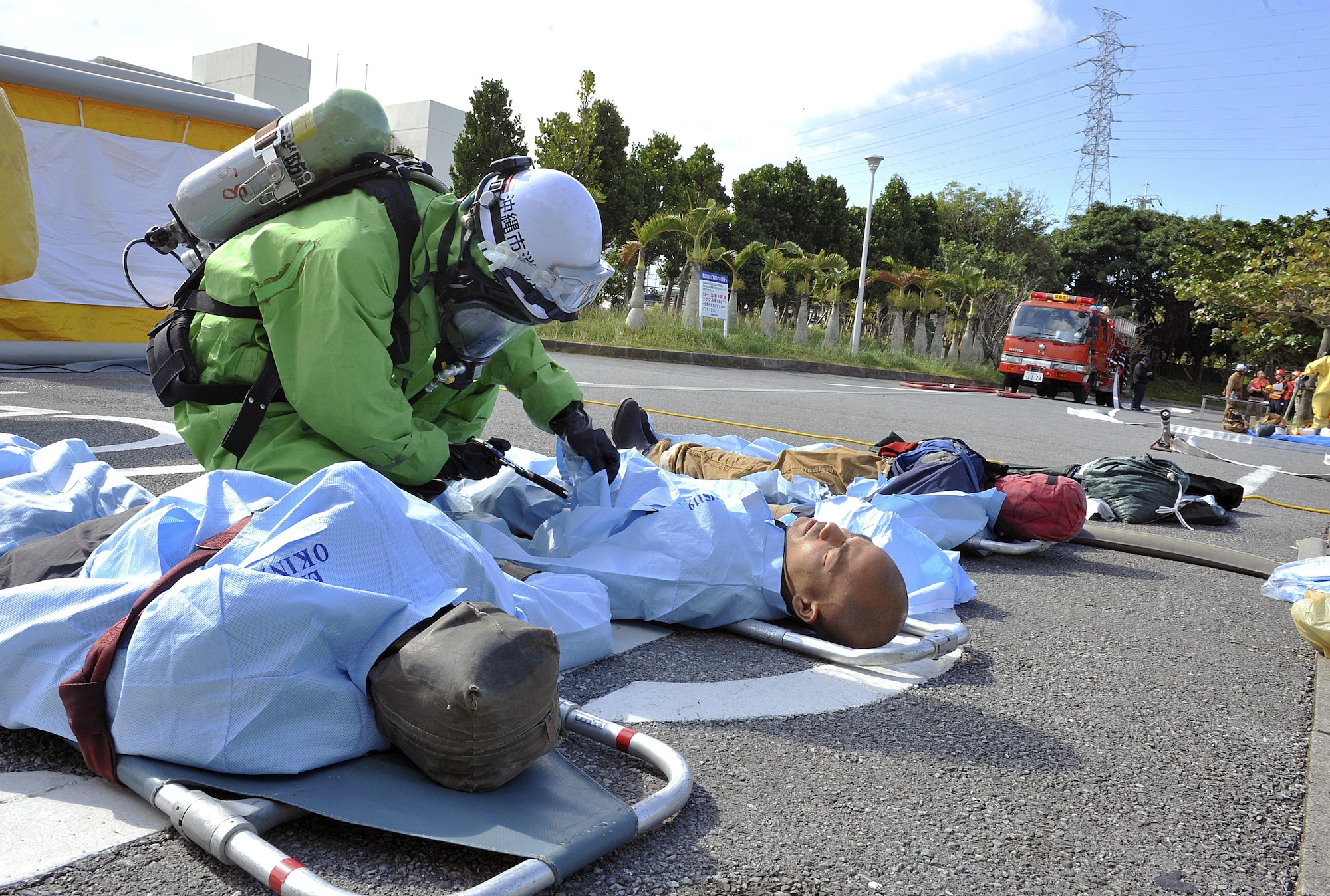 Members of Okinawa City Fire Department cut through contaminated clothing of mock victims during a bilateral hazardous materials training exercise, Dec. 8, 2015, at the Okinawa City Civic Center, Japan. The Kadena fire department conducts bilateral training exercises occasionally in order to further develop the cooperation and teamwork necessary to combat any type of hazardous materials threat with their local counterparts. (U.S. Air Force photo by Naoto Anazawa)