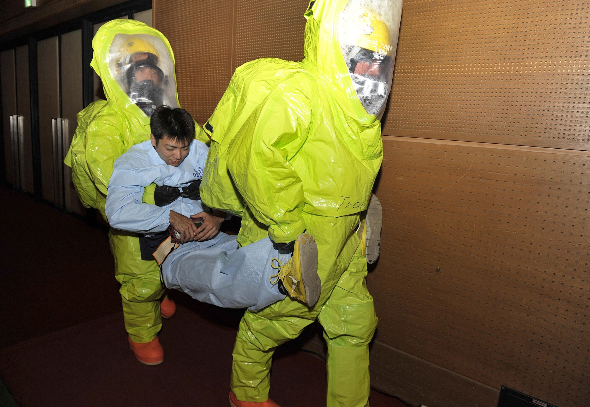 Moritaka Shiroma, 18th Civil Engineer Squadron firefighter (left), and U.S. Air Force Senior Airman Emily Beckerjeck, 18th CES driver operator (right), carry a simulated casualty to safety during a bilateral hazardous materials training exercise, Dec. 8, 2015, at the Okinawa City Civic Center, Japan. This is the first time Kadena Fire Department participated in an off-base exercise scenario hosted by Okinawa City Fire Department. (U.S. Air Force photo by Naoto Anazawa)
