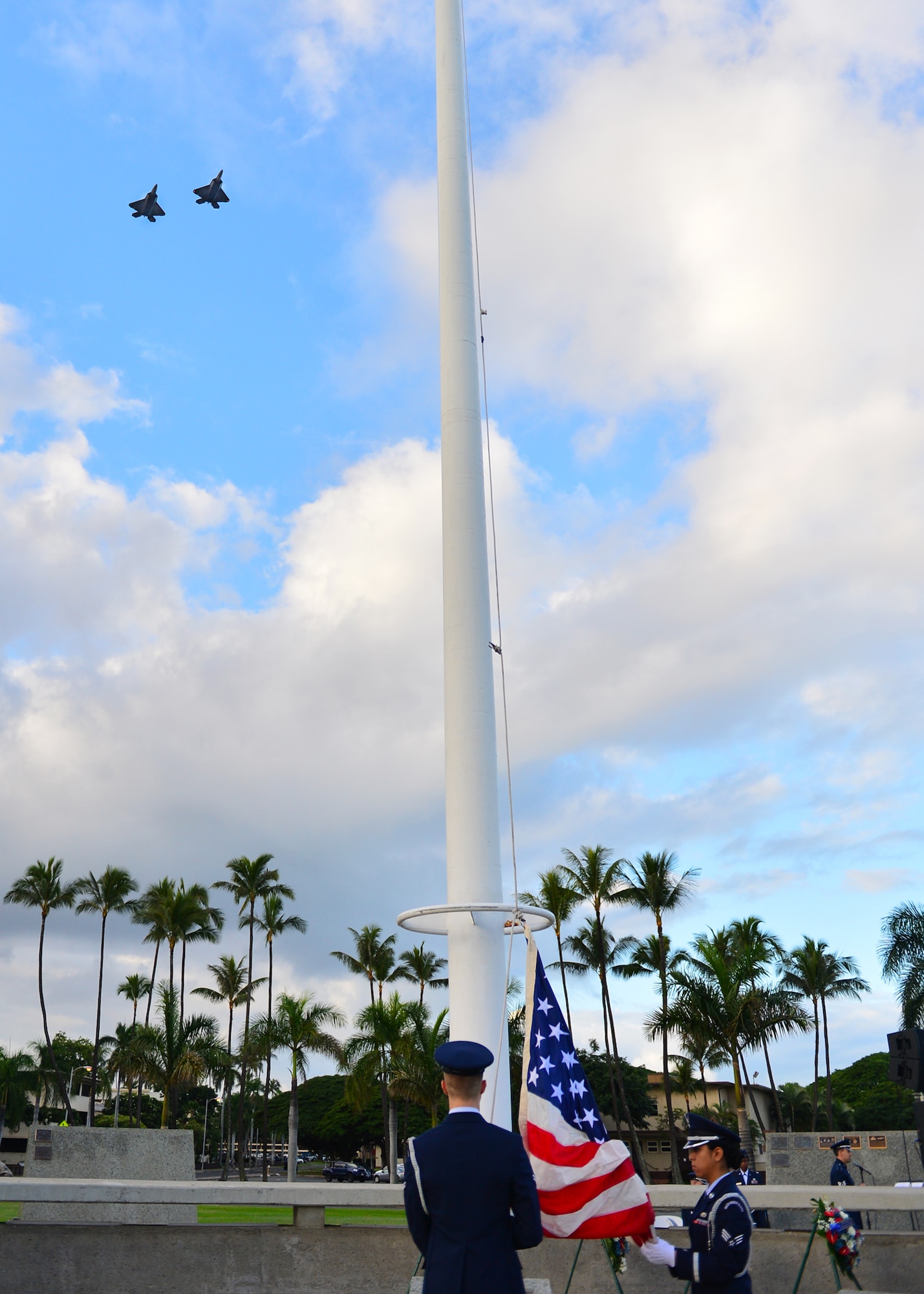 Members of the Hickam Honor Guard perform flag detail as two F-22 Raptors fly over during the 74th attack on Hickam Field Remembrance Ceremony hosted by the 15th Wing on Joint Base Pearl Harbor-Hickam, Hawaii, Dec. 7, 2015. Survivors and their family members attended the ceremony, which honors the men and women who lost their lives on Hickam Field during the two waves of attacks launched by the Imperial Japanese Navy on Dec. 7, 1941. (U.S. Air Force photo by Tech. Sgt. Aaron Oelrich/Released) 
