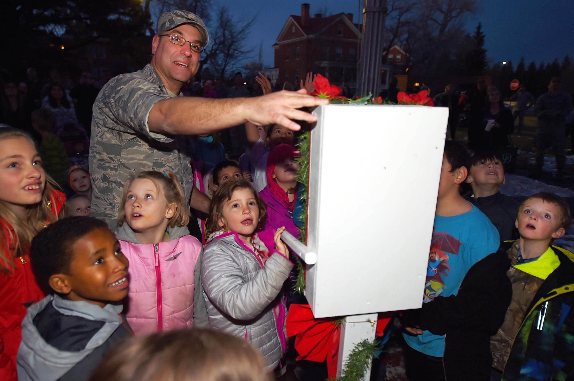 Children of the F.E. Warren Air Force Base, Wyo., community help Col. Stephen Kravitsky, 90th Missile Wing commander, flip the switch lighting the base's holiday tree Dec. 4, 2015. After the lighting, the festivities moved into the Fall Hall Community Center where children were able to visit with Santa and Mrs. Claus, decorate cookies and other crafts, and their parents strolled through stalls selling a wide assortment of craft items. (U.S. Air Force photo by R.J. Oriez)