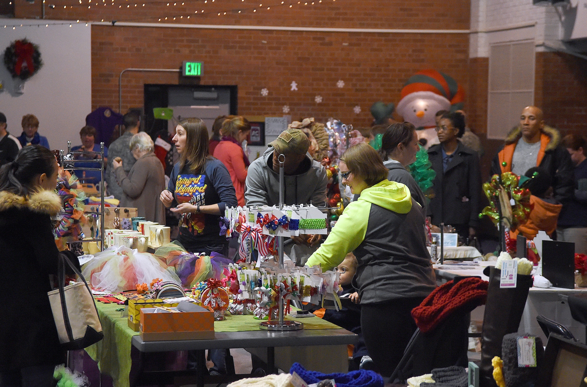 Airmen and family members stroll through stalls featuring crafts and baked goods in the Fall Hall Community Center on F.E. Warren Air Force Base, Wyo., Dec. 4, 2015. The opportunity to gift shop was part of the annual base tree lighting festivities. (U.S. Air Force photo by R.J. Oriez)