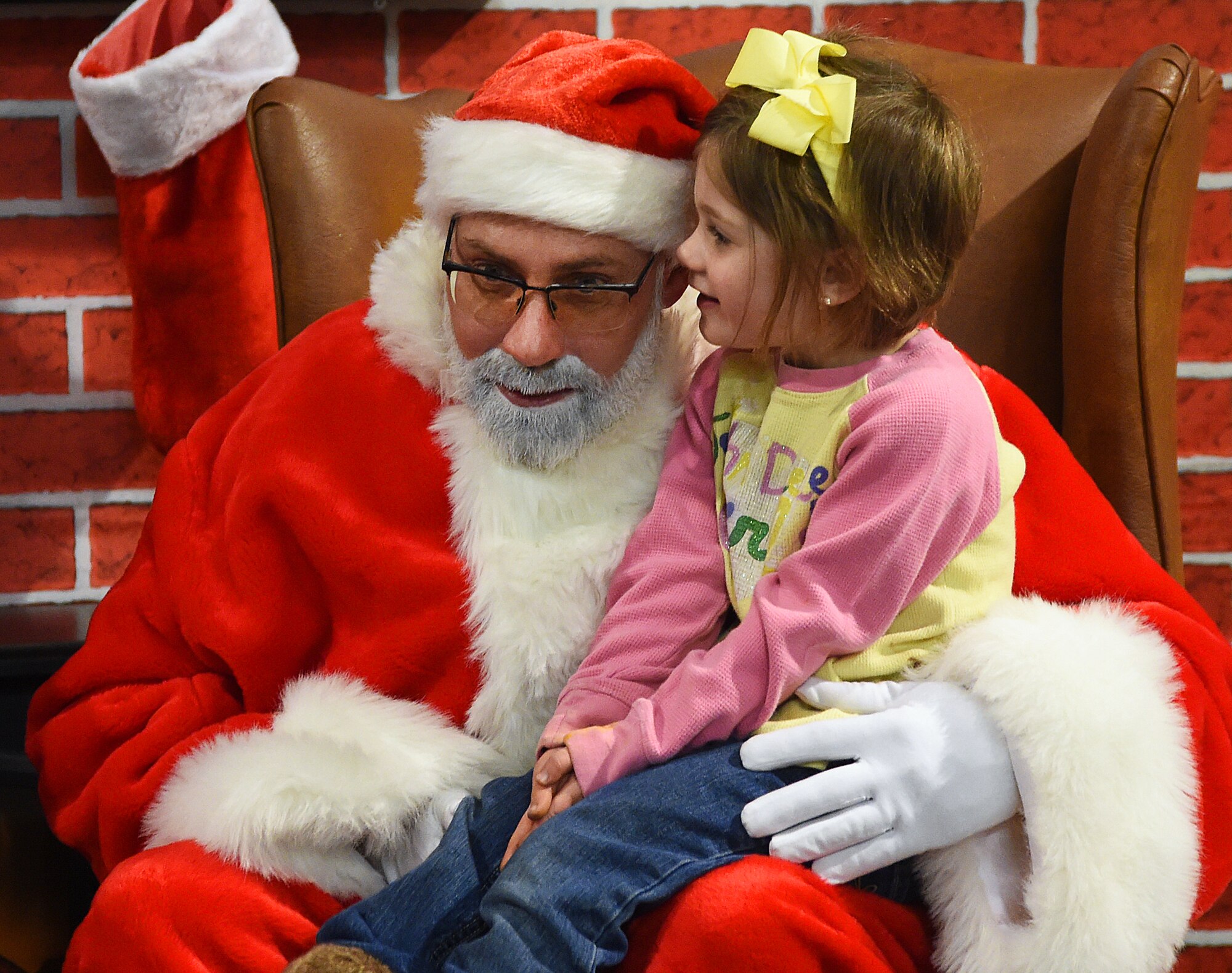 Brooklyn Houghton, 4, whispers into Santa's ear as he listens to what she wants for Christmas this year. Brooklyn, the daughter of Julie and Staff Sgt. Eric Houghton, Air Force Global Strike Command missile engineering office got the chance to visit with Santa Dec. 4, 2015, following the F.E. Warren Air Force Base, Wyo., annual tree lighting ceremony. (U.S. Air Force photo by R.J. Oriez.)