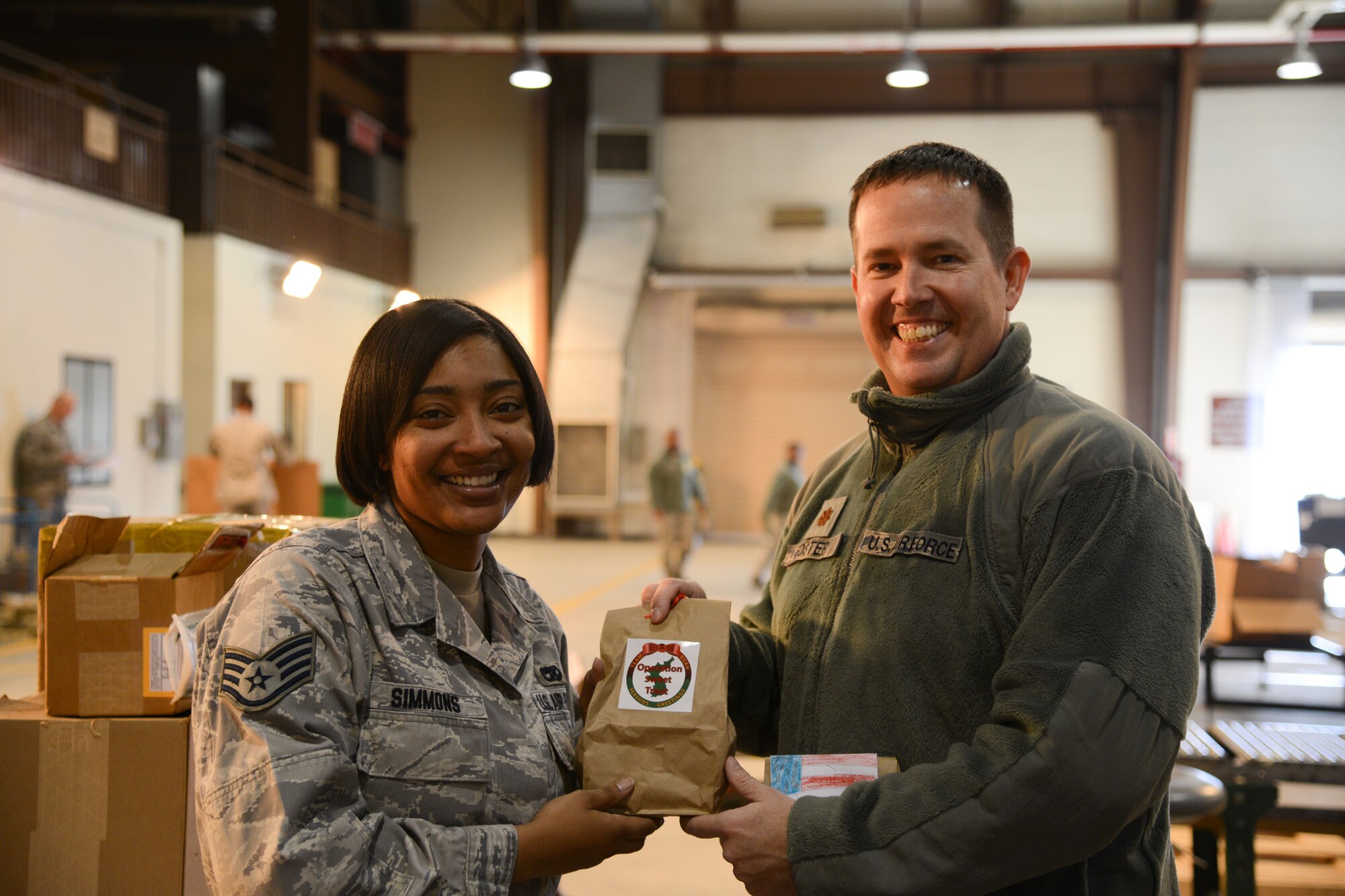 Maj. Timothy Foster, right, 51st Logistics Readiness Squadron commander, poses for a photo with Staff Sgt. Ashley Simmons, 51st LRS freight documentation supervisor, during Operation Sweet Treat at Osan Air Base, Republic of Korea, Dec. 8, 2015. Team Osan volunteers baked more than 108,000 cookies for commanders and first sergeants to deliver to the base’s unaccompanied Airmen. (U.S. Air Force photo/Airman 1st Class Dillian Bamman)